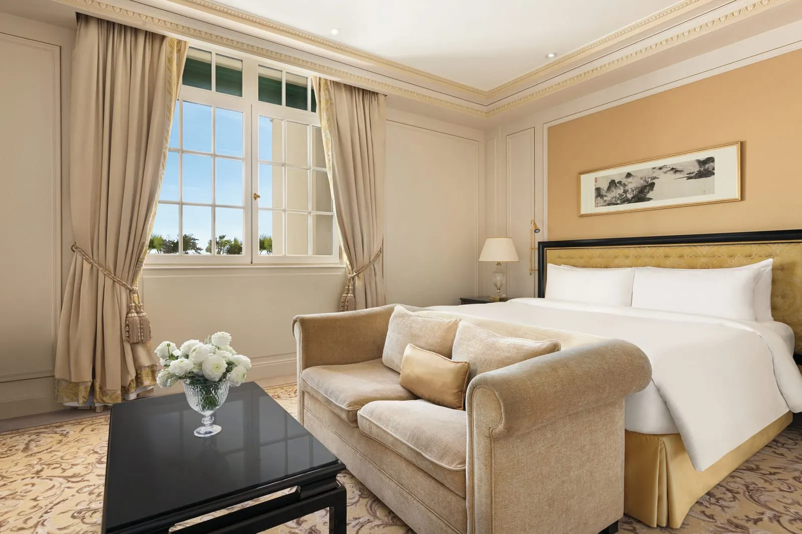 Terrace Suite with Paris View at Shangri-La Paris: the bedroom, with a king bed, a velvet sofa at its foot, a black lacquered coffee table and a tall window