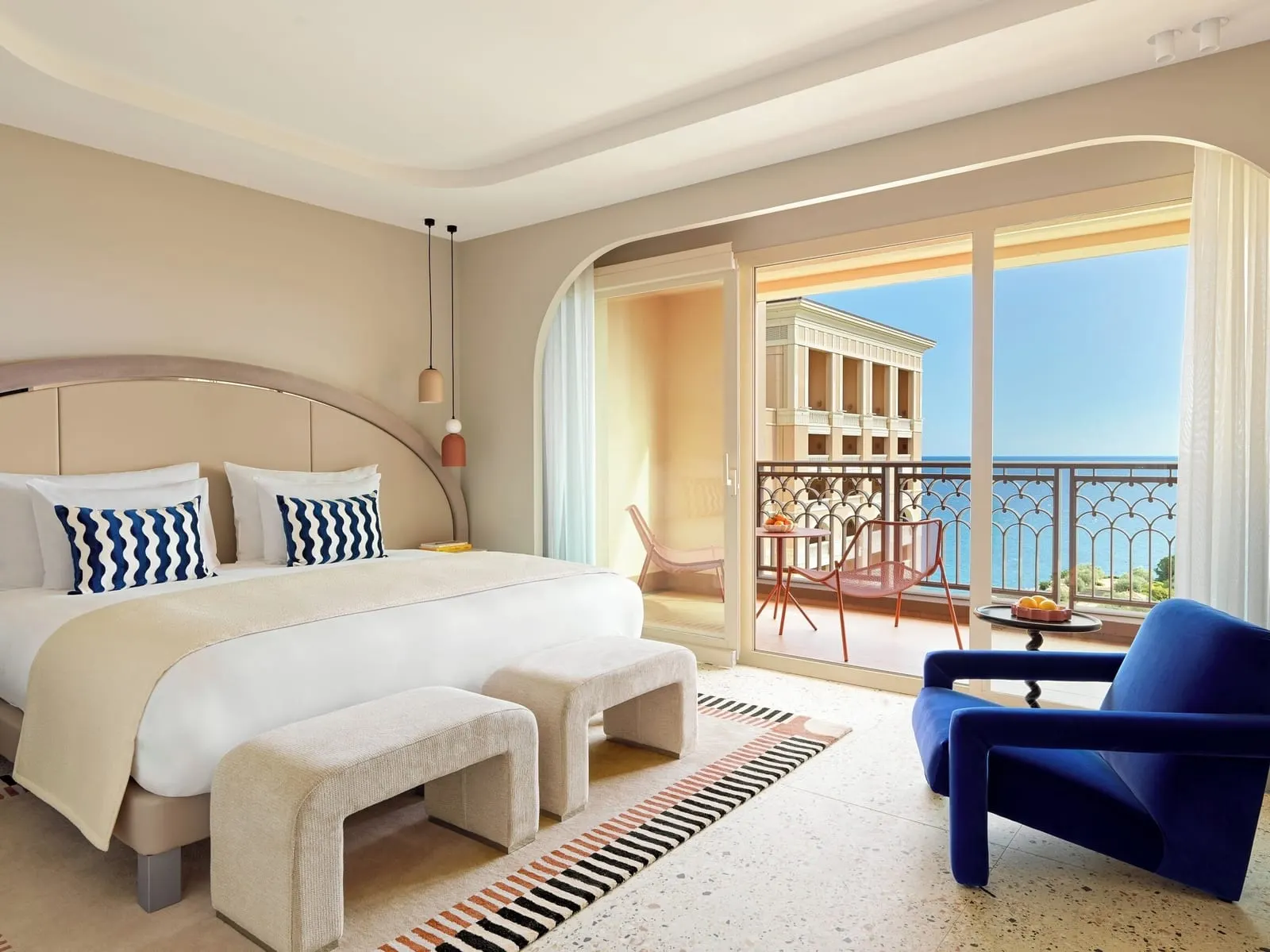 Exclusive Premium Room with sea view at Monte-Carlo Bay Hotel & Resort: the bed, a blue armchair and glass doors to the terrace and the sea
