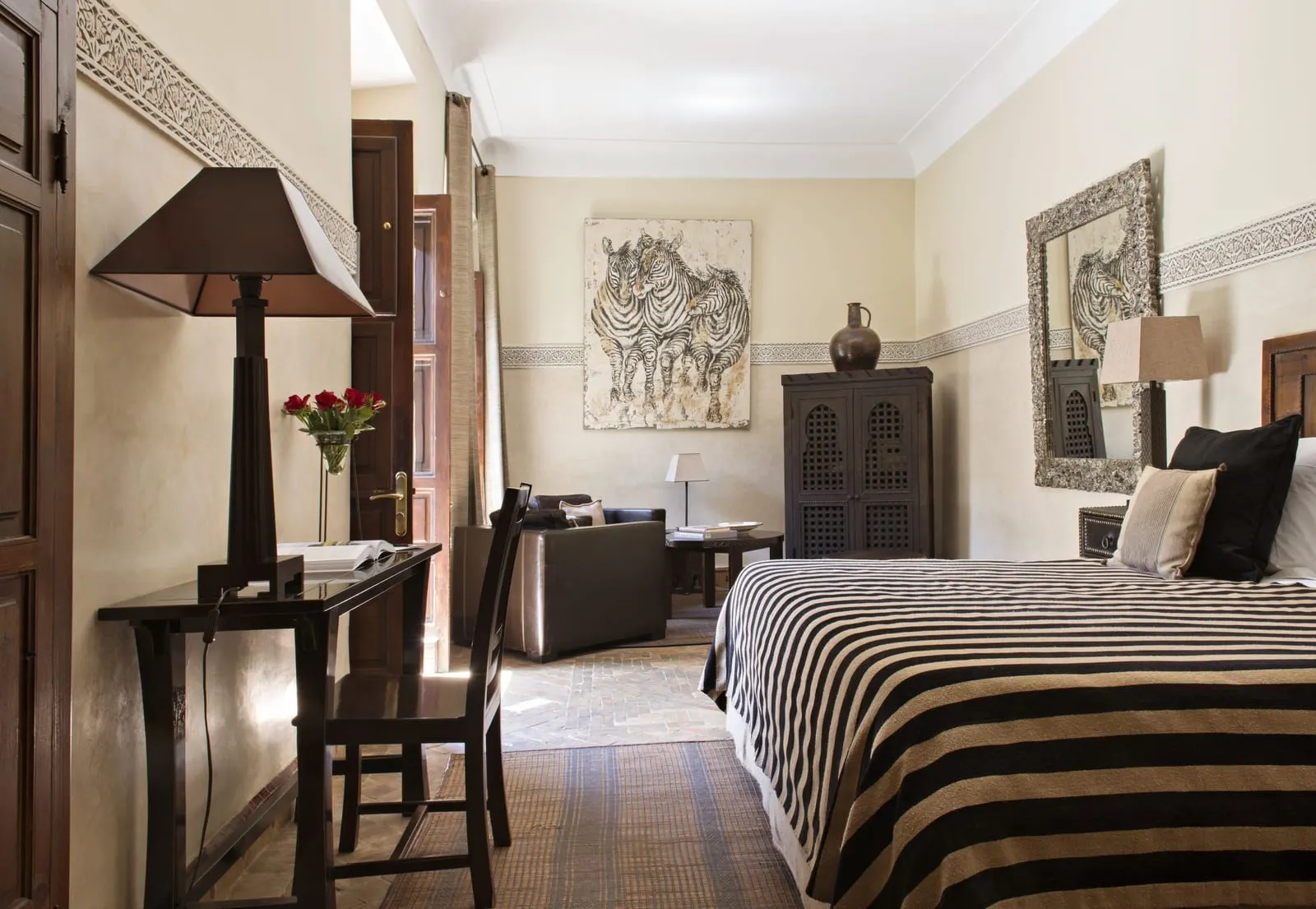 Small Suite with Terrace at La Villa des Orangers: a double bed with a striped cover, a writing desk and a seating corner beyond.