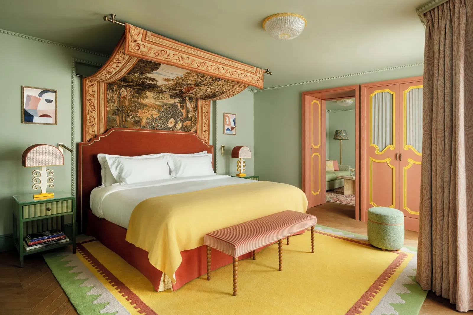 Mazarin Suite at Le Grand Mazarin: a bed under a tapestry canopy with a striped bench at its foot, and double doors open onto the sitting room beyond