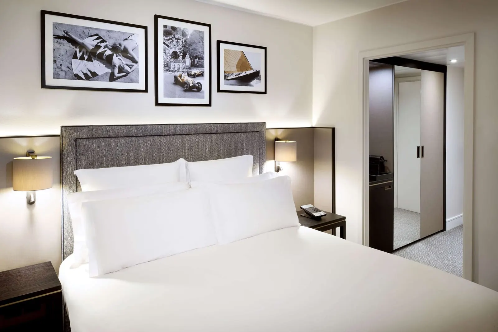 Riviera Deluxe Room at Columbus Hotel Monte-Carlo: the bed with a grey upholstered headboard and three framed prints above