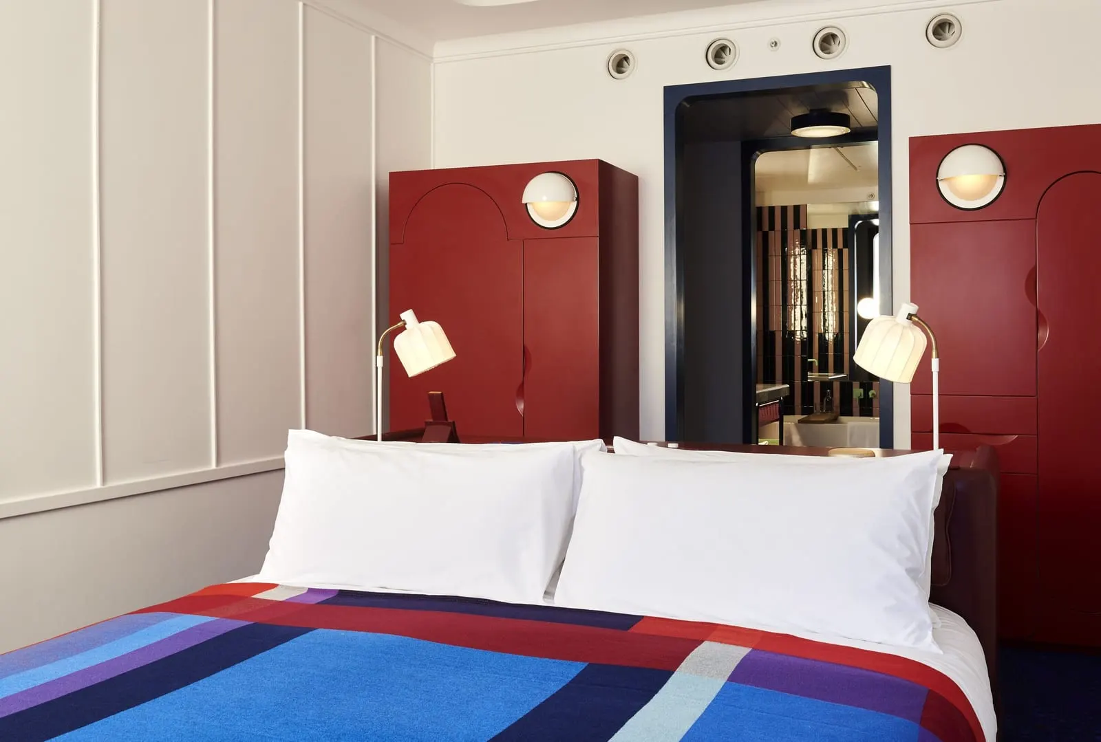 Premium King at The Standard, London: the bed with a striped blanket, red wardrobes and a doorway to the bathroom