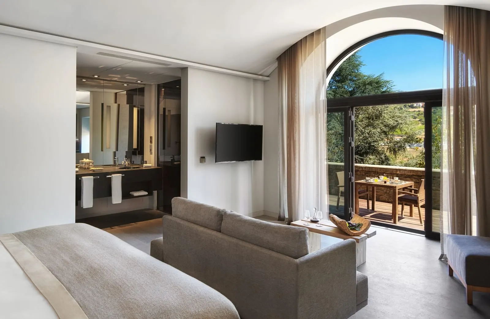 Quinta River at Six Senses Douro Valley: a sofa and arched glass doors open to a terrace with a breakfast table