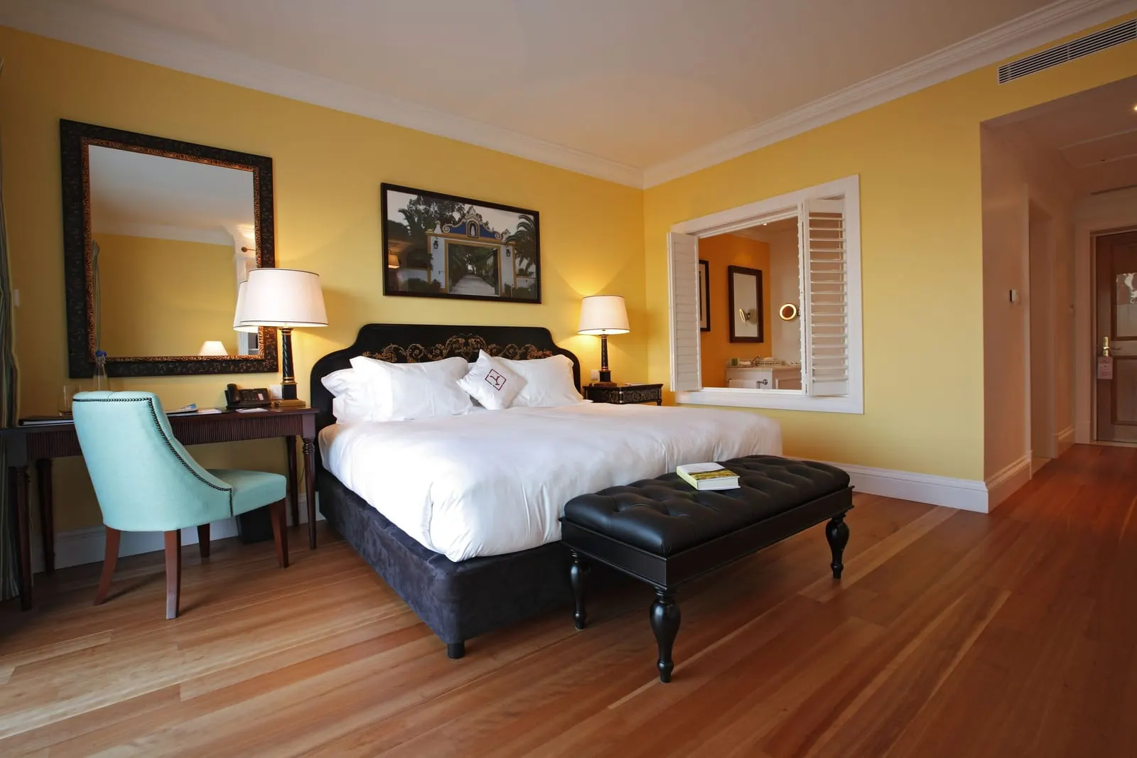 Superior Room at The Yeatman: the bed with a leather bench, a desk and chair on a wooden floor, and an interior window with shutters