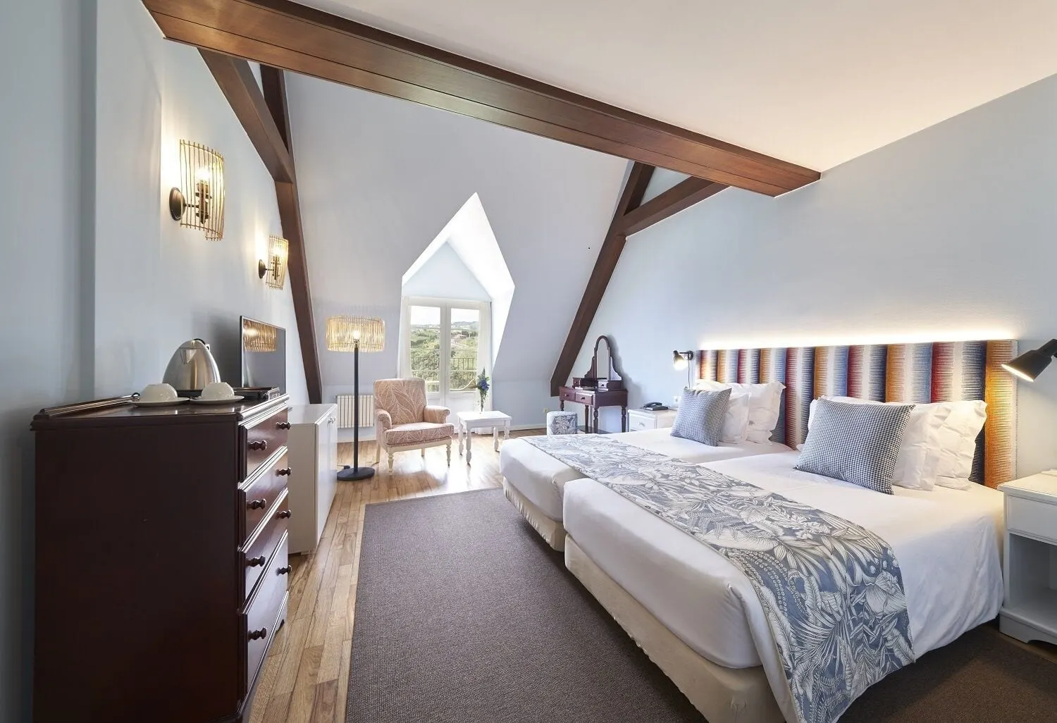 Premium Room at Hotel Quinta do Furão: two single beds made up as a double under a striped headboard, in a pale blue attic room with dark wooden beams, a chest of drawers and a glazed door in a dormer