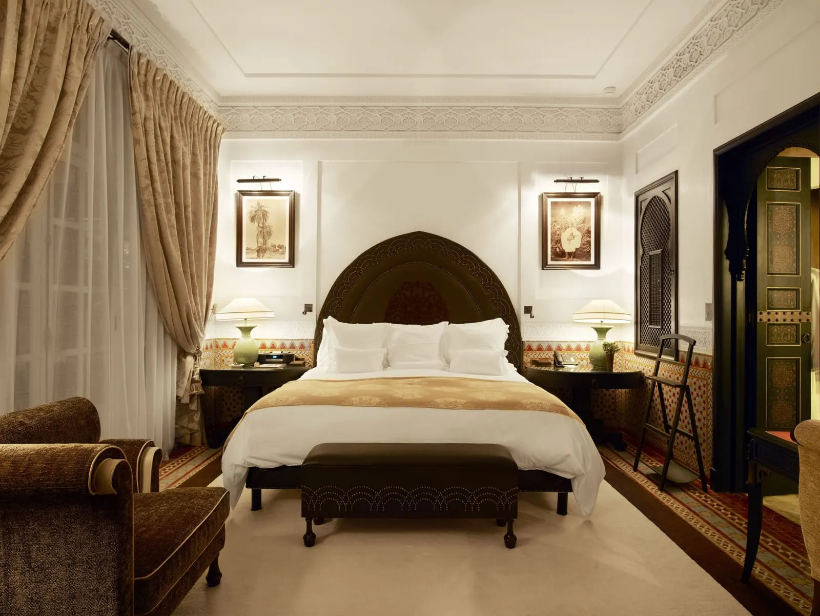 Exceptional Suites at La Mamounia: the Koutoubia Suite bedroom, a king bed under a carved headboard between two framed prints