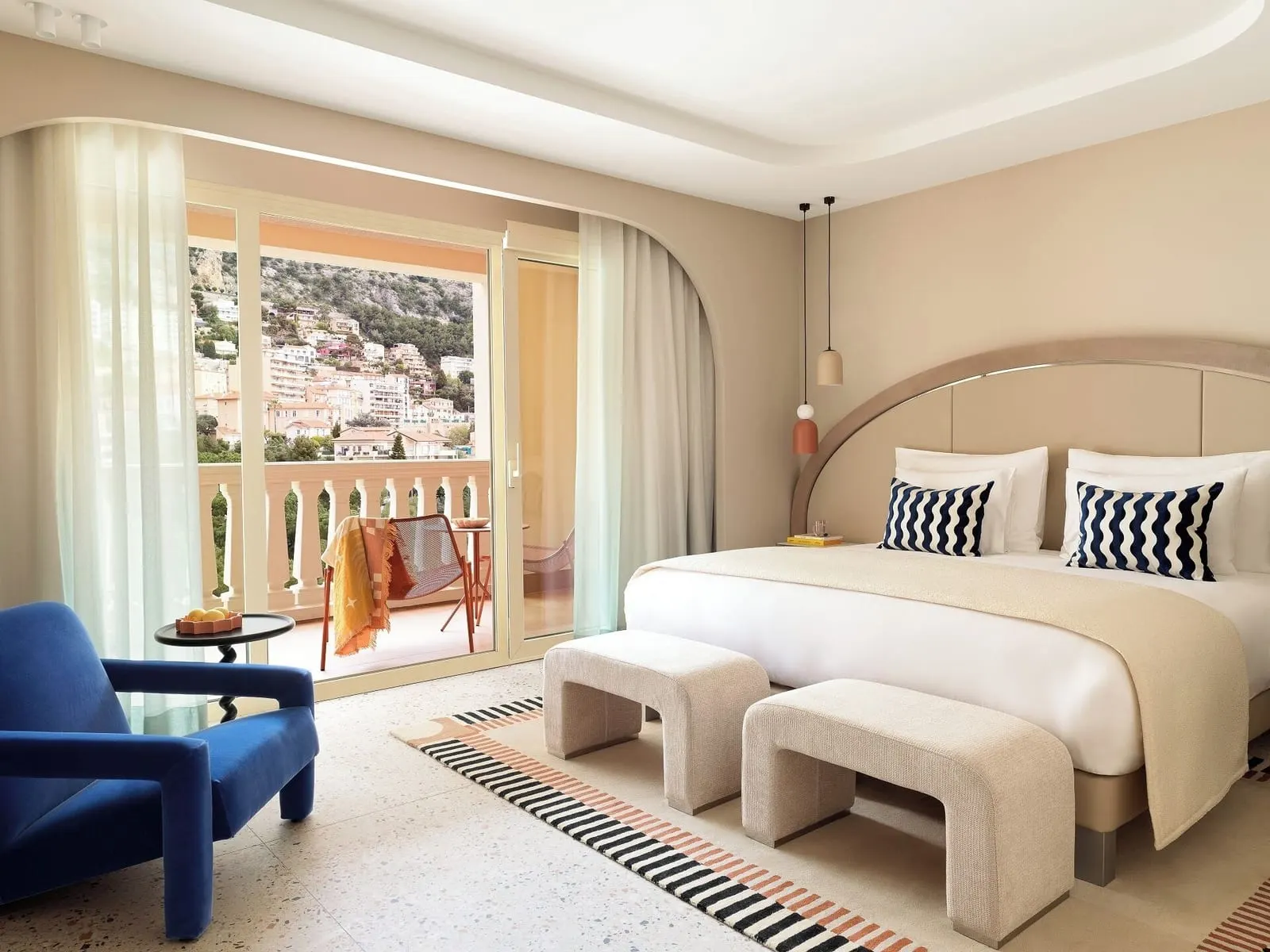 Deluxe Premium Room with city view at Monte-Carlo Bay Hotel & Resort: the bed, two benches and a blue armchair by the terrace