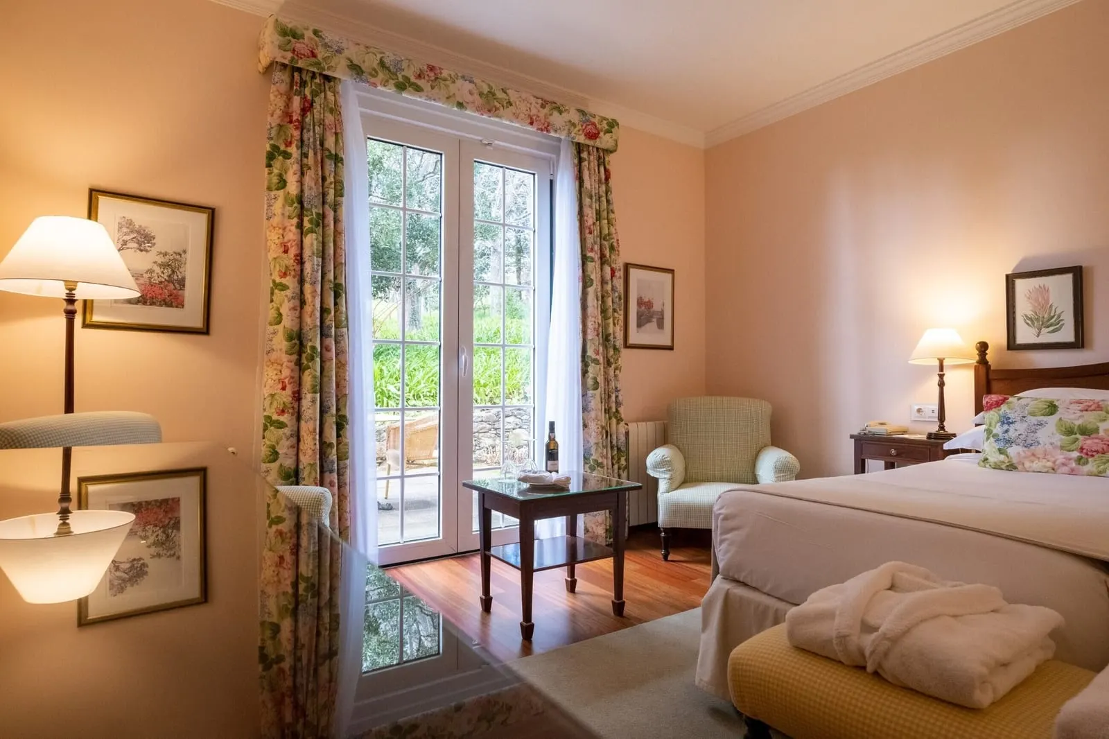 Double Golf Wing at Casa Velha do Palheiro, Relais & Châteaux: glazed doors open onto a small patio, with an armchair and a side table beside the bed