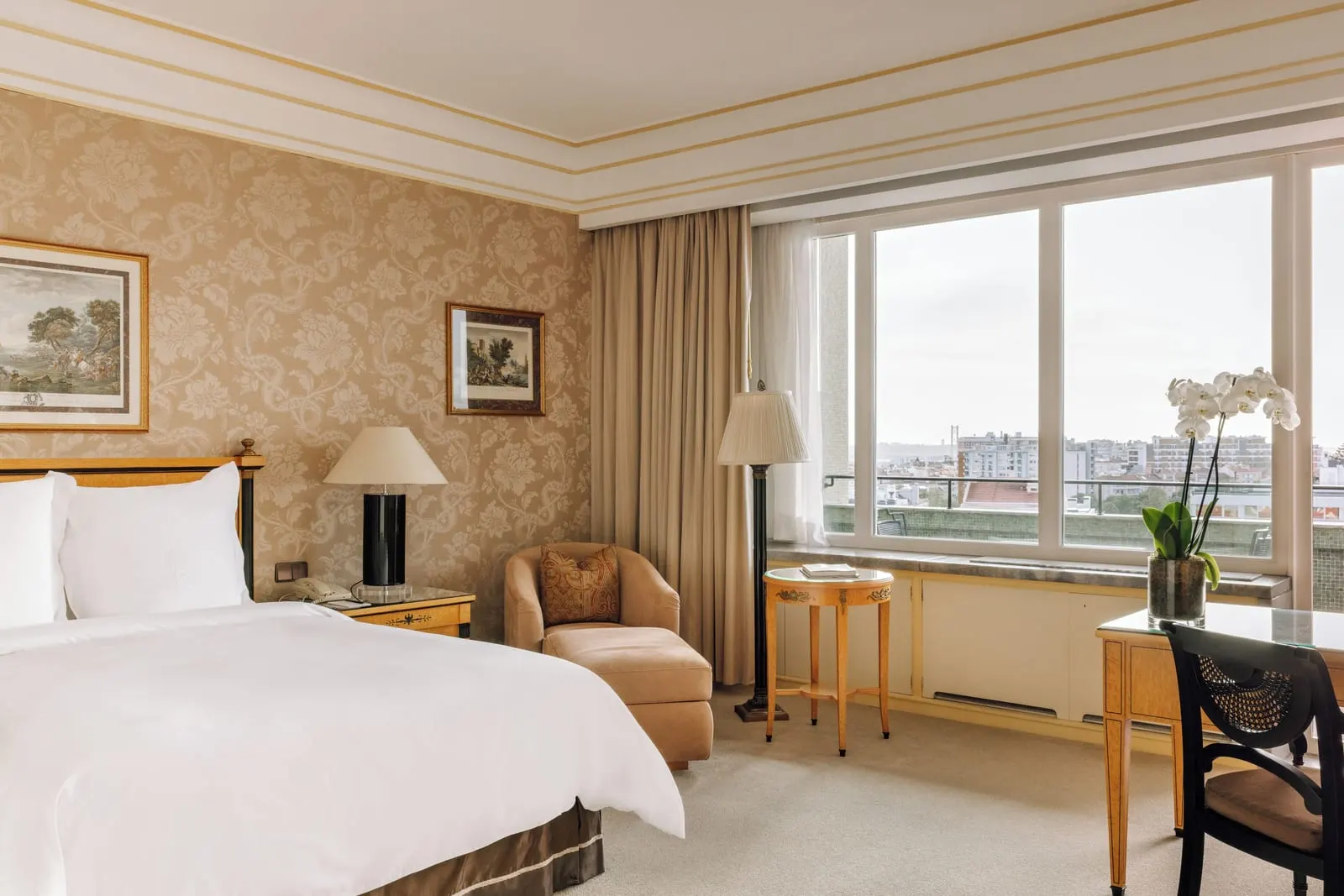 Superior Room at Four Seasons Ritz Lisbon: the bed, an armchair and a desk against damask walls, by a wide window