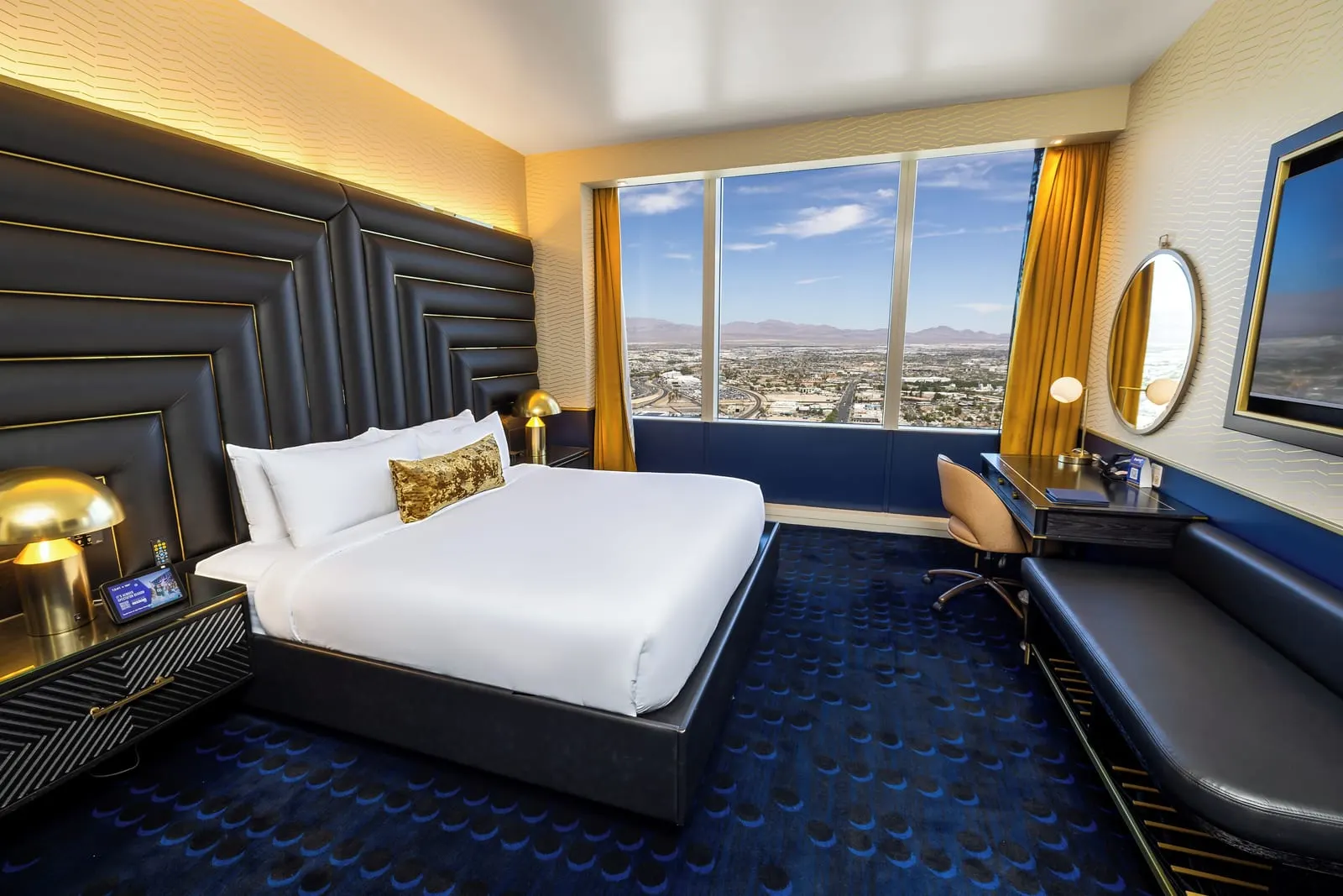 Circa Suite al Circa Resort & Casino: la camera da letto, con un letto king contro un'alta testiera imbottita nera, una scrivania, una lunga panca e un'ampia finestra sulla città