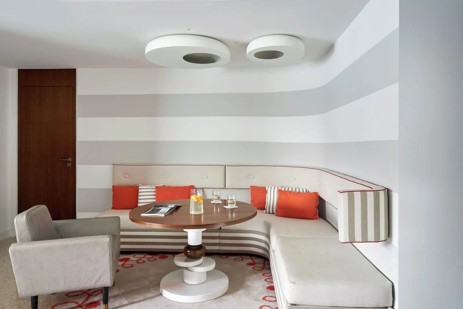 Junior Suite at Monte-Carlo Beach: the sitting corner with a white banquette, orange cushions and a round table