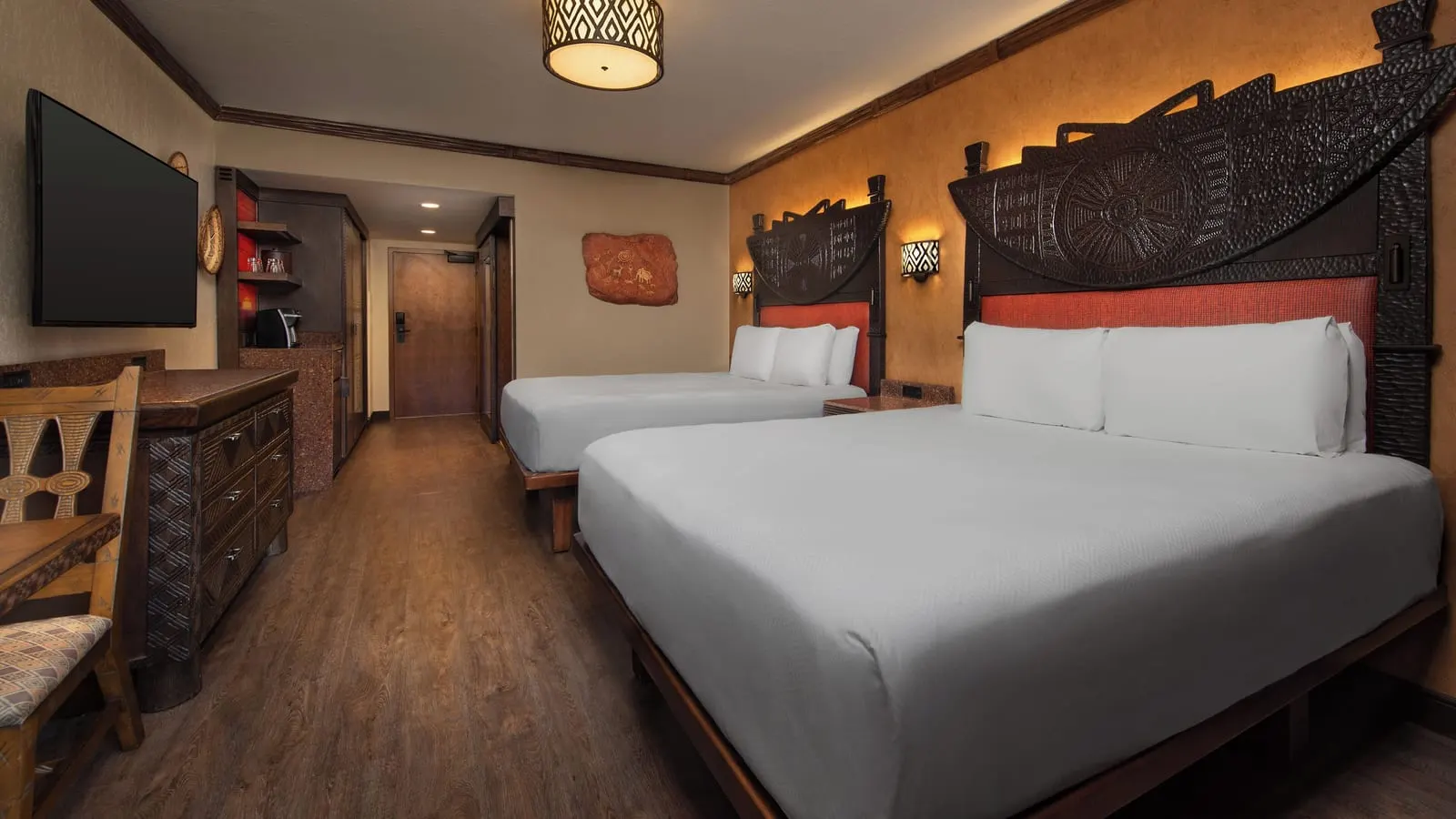 Savanna View room at Disney's Animal Kingdom Lodge: two queen beds with carved wooden headboards, a chest of drawers, a wall-mounted television and a coffee station by the door