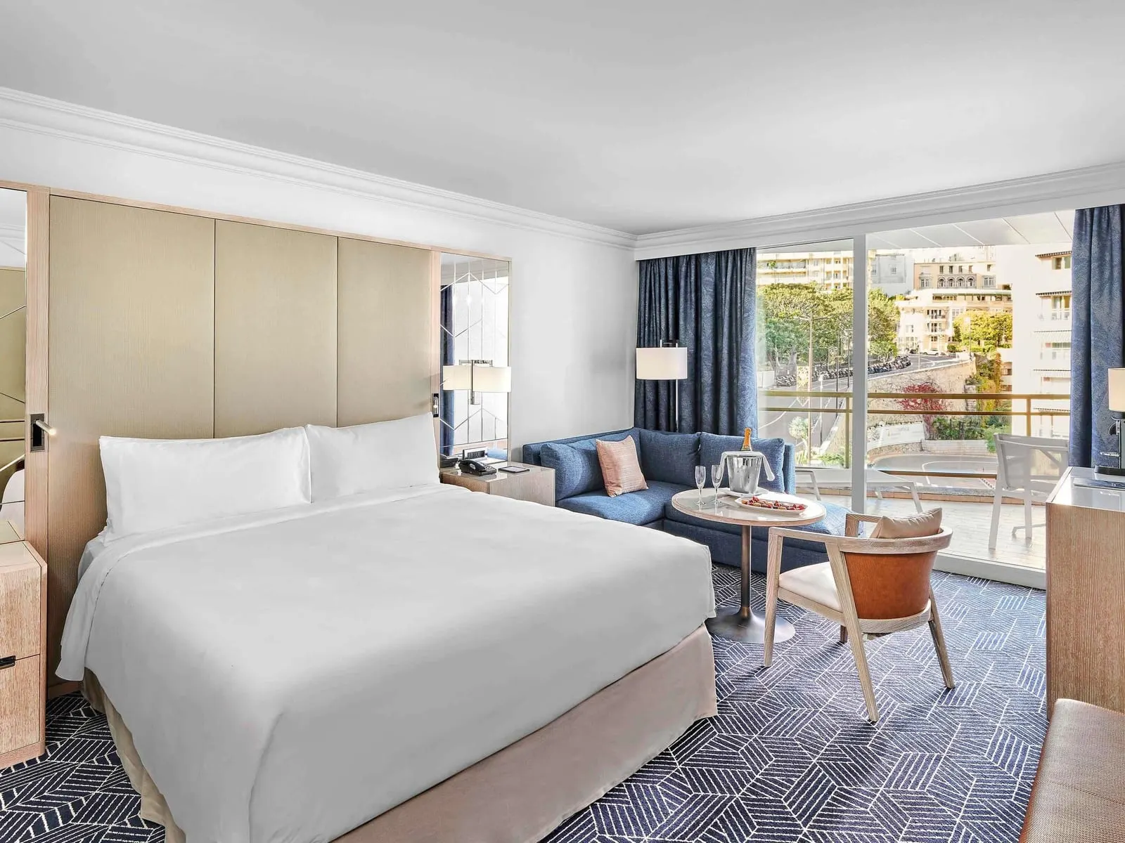 Hairpin City View room at Fairmont Monte Carlo: the bed, a sofa and a window onto the terrace and the city