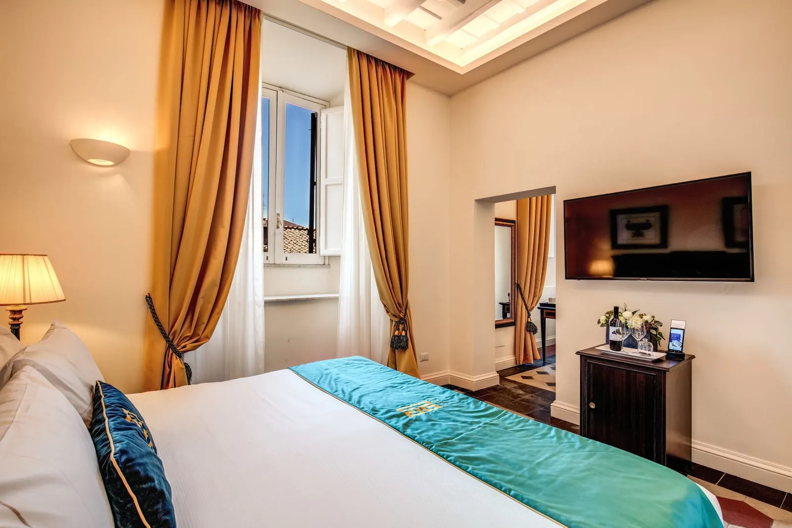 Superior Suite at Eitch Borromini Palazzo Pamphilj: a double bed with a teal throw, gold curtains and a doorway to the next room
