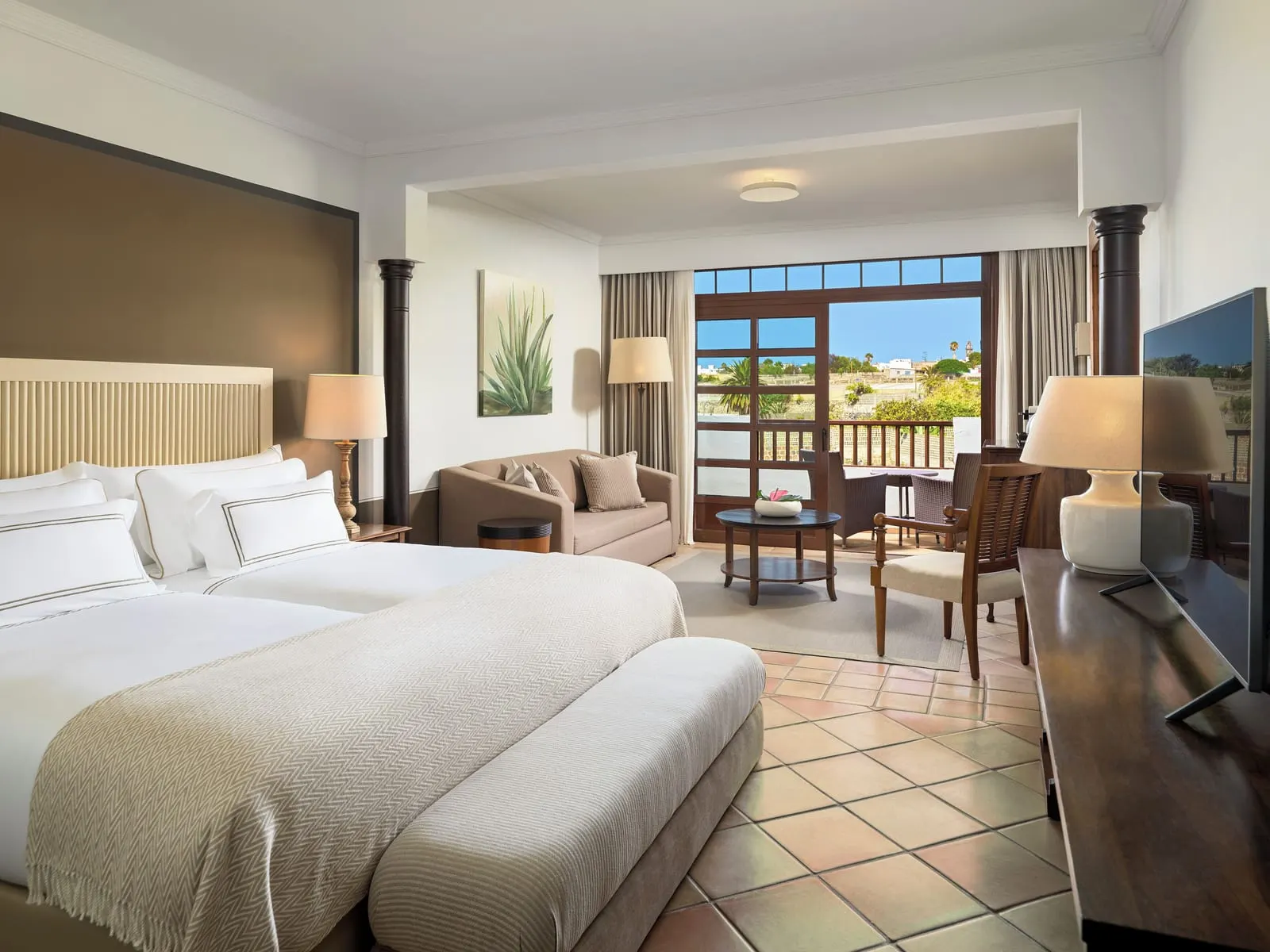 Singular Junior Suite at Hacienda del Conde: two beds made up as one, a sofa and a table by the terrace doors