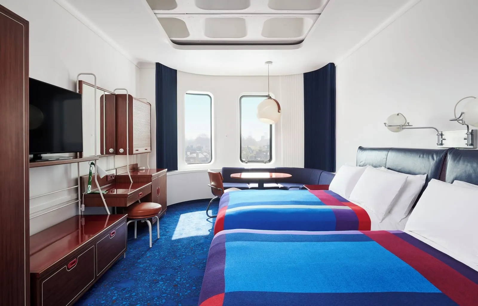 Standard Double with Two Double Beds at The Standard, London: two beds with blue blankets, a desk and round-cornered windows