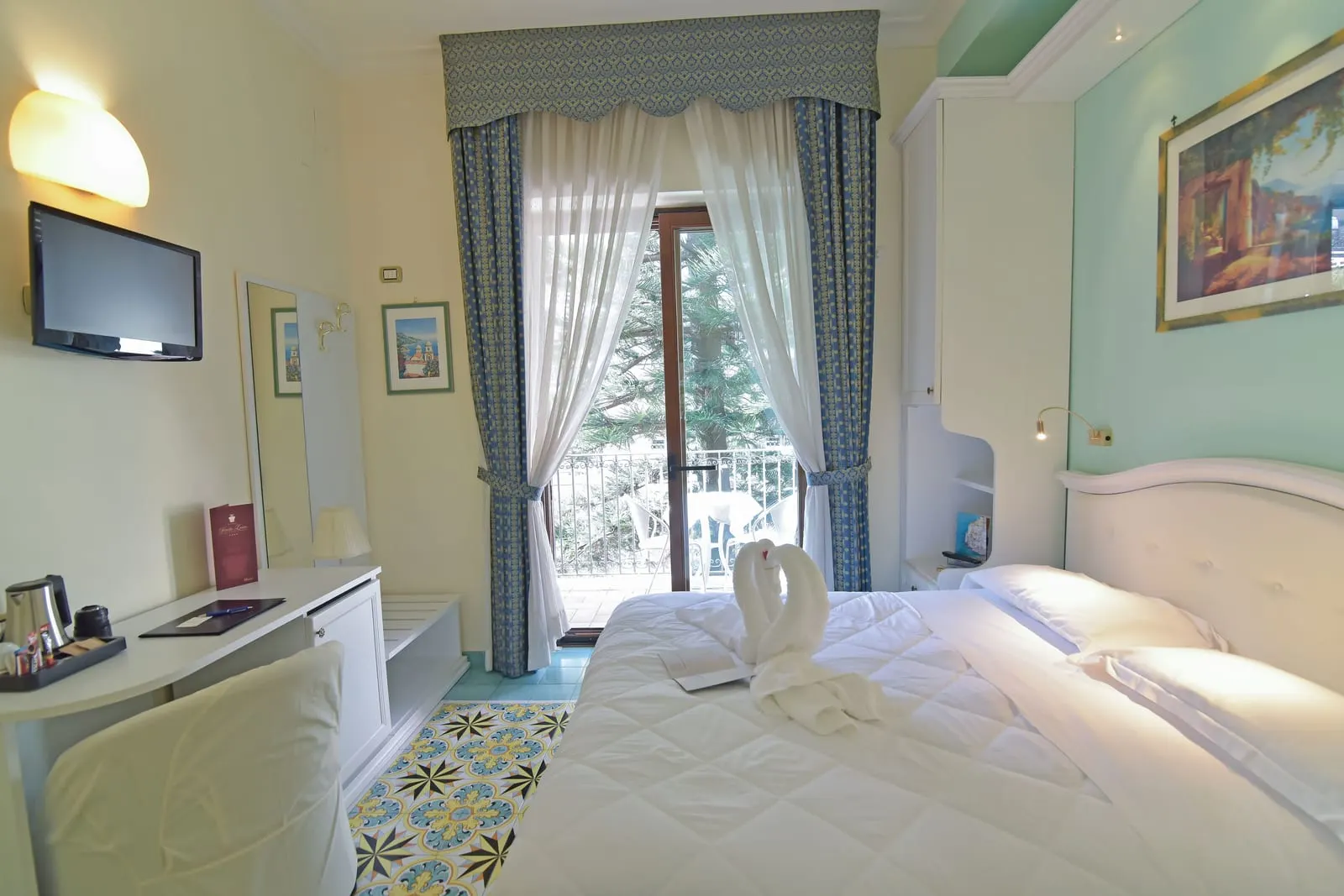 Classic Double at Hotel Santa Lucia: a double bed facing a desk and a glass door onto a balcony with a table and chairs