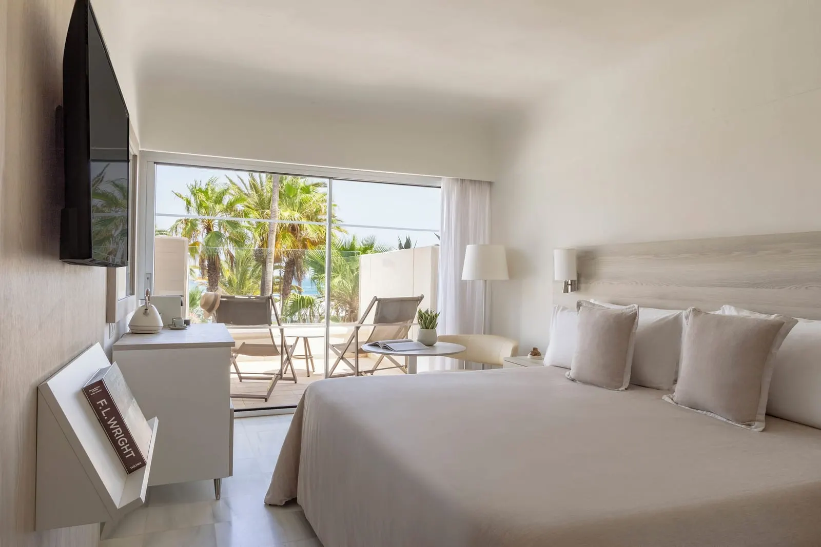 Premium Resort View at Paradisus Salinas Lanzarote: a king bed facing a sliding window onto a terrace with two lounge chairs and palm trees