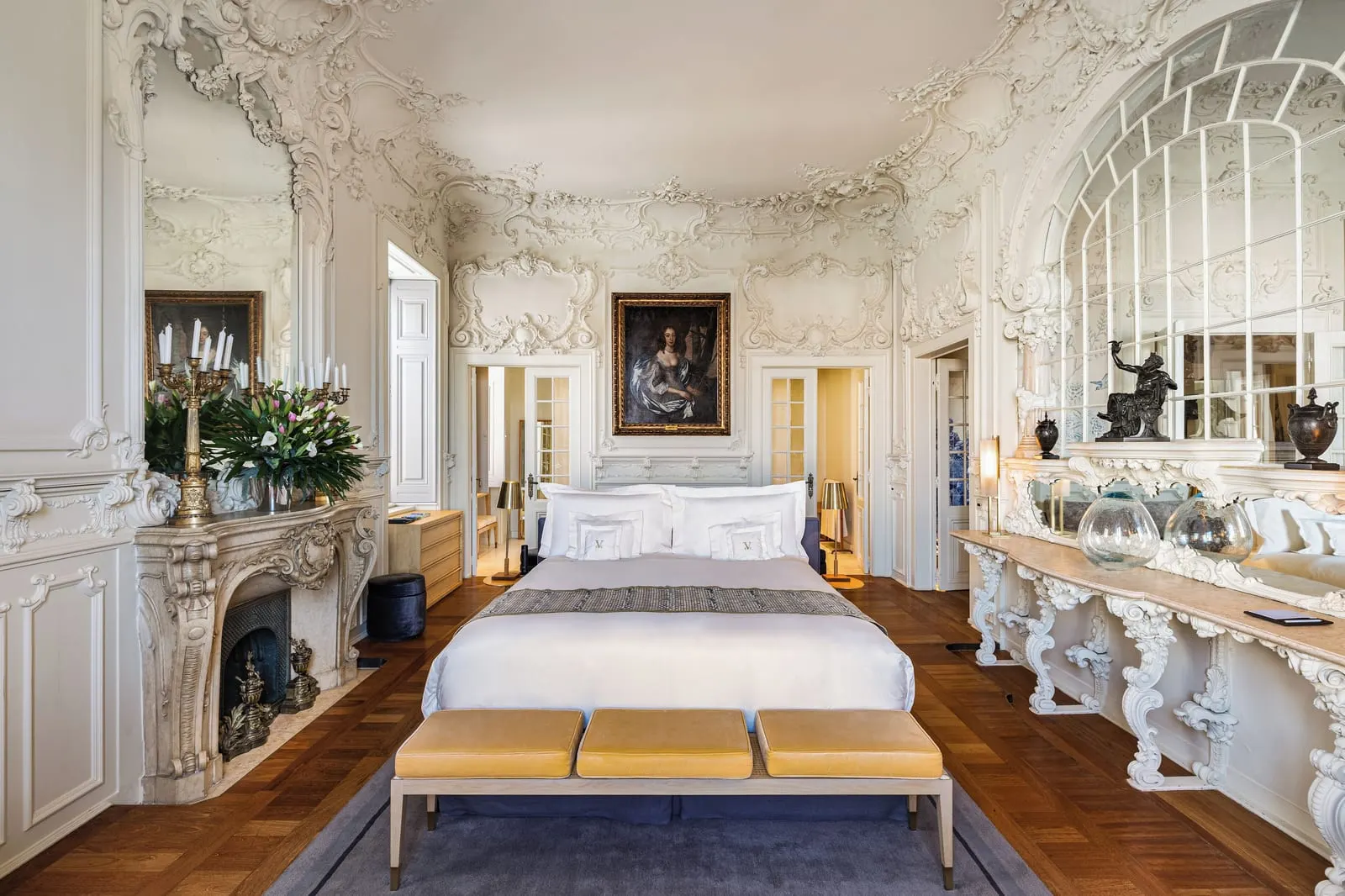 The Queen Suite, one of the Royal Suites at Verride Palácio Santa Catarina: ornate stucco walls, a carved fireplace and the bed