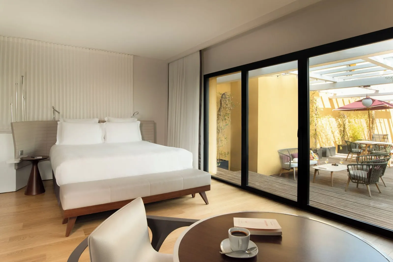 Executive Room with Terrace at Hôtel Molitor Paris: a king-size bed and floor-to-ceiling glass doors onto the private terrace, with a pergola, plants and outdoor seating