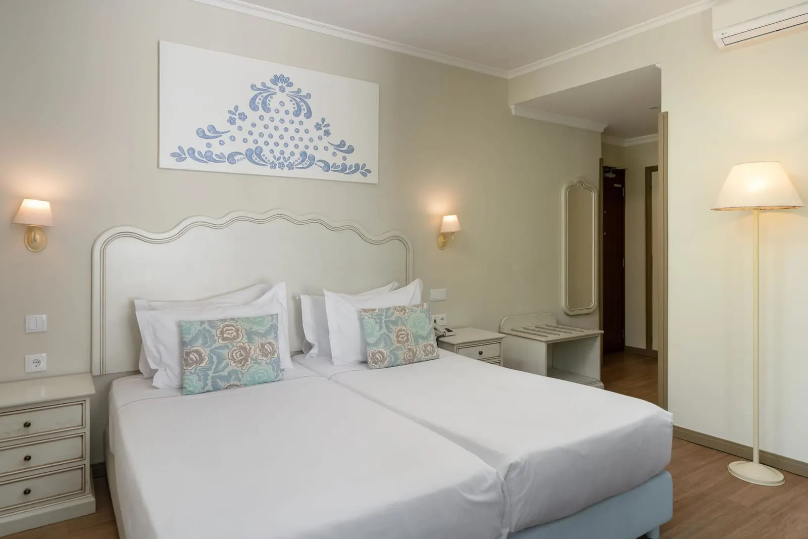 Superior Room im Hotel Madeira: zwei Einzelbetten unter einem geschwungenen weißen Kopfteil, mit Nachttischlampen und einer Stehlampe