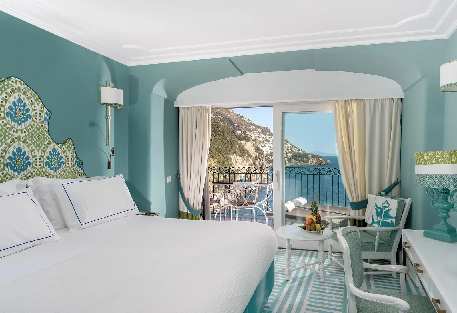 Classic Room at Il San Pietro di Positano: a double bed against teal walls, with glass doors open to a small terrace over the sea