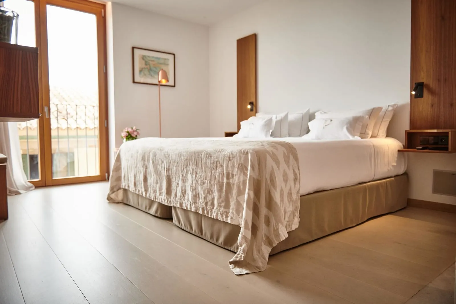 Superior at Es Princep: a double bed with a woven bedspread and a balcony door onto the tiled rooftops of the old town
