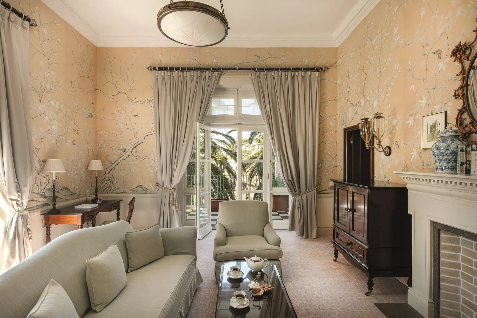 Winston Churchill Suite at Reid's Palace, A Belmond Hotel: a sitting room with a fireplace, hand-painted wallpaper and doors open to a balcony