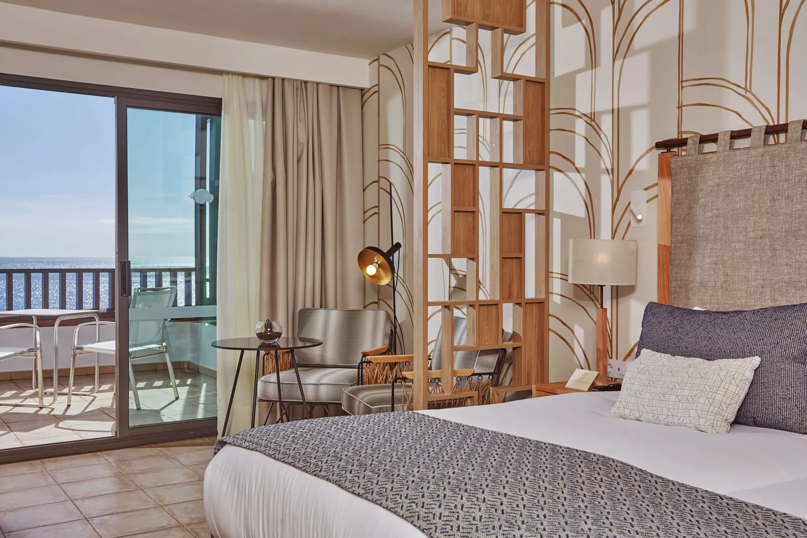 Preferred Club Junior Suite Ocean View al Secrets Lanzarote Resort & Spa: un letto dietro un divisorio a scaffali, con porte del balcone e una terrazza a sinistra