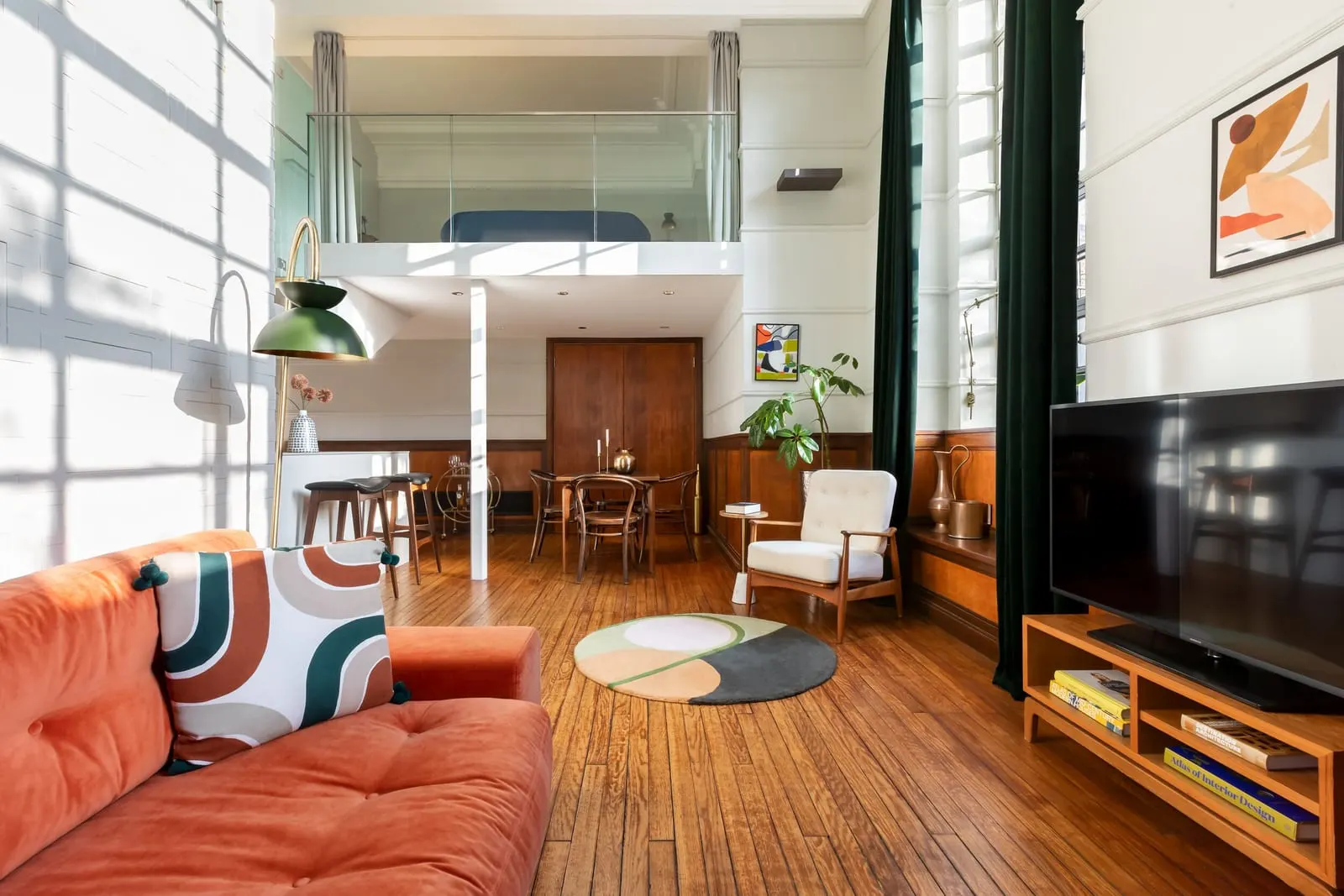 Signature Two Bedroom Suite at Town Hall Hotel: an orange sofa and a television below a mezzanine with a glass rail