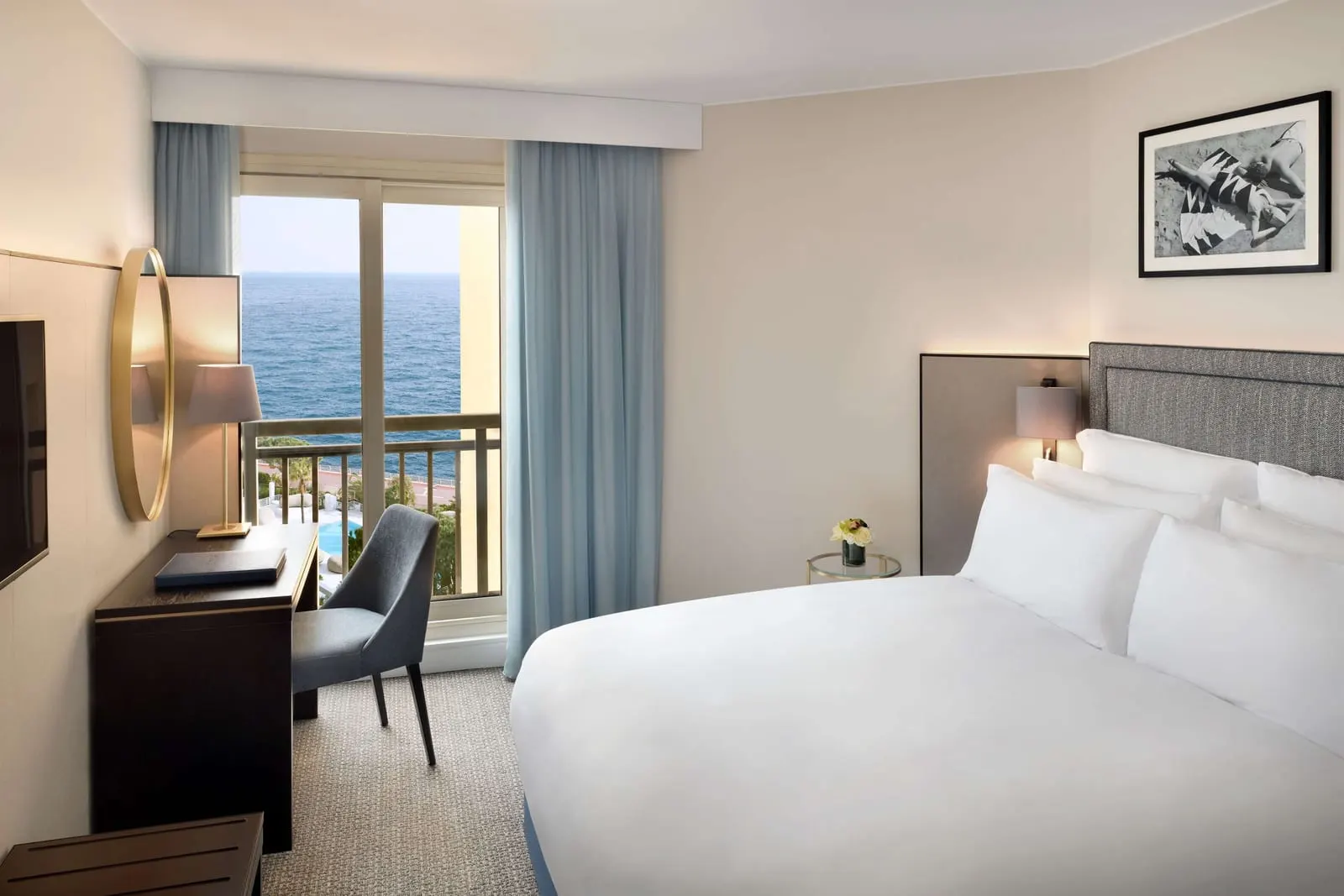 Riviera Room at Columbus Hotel Monte-Carlo: the bed, a desk and a window to a balcony with a view of the sea
