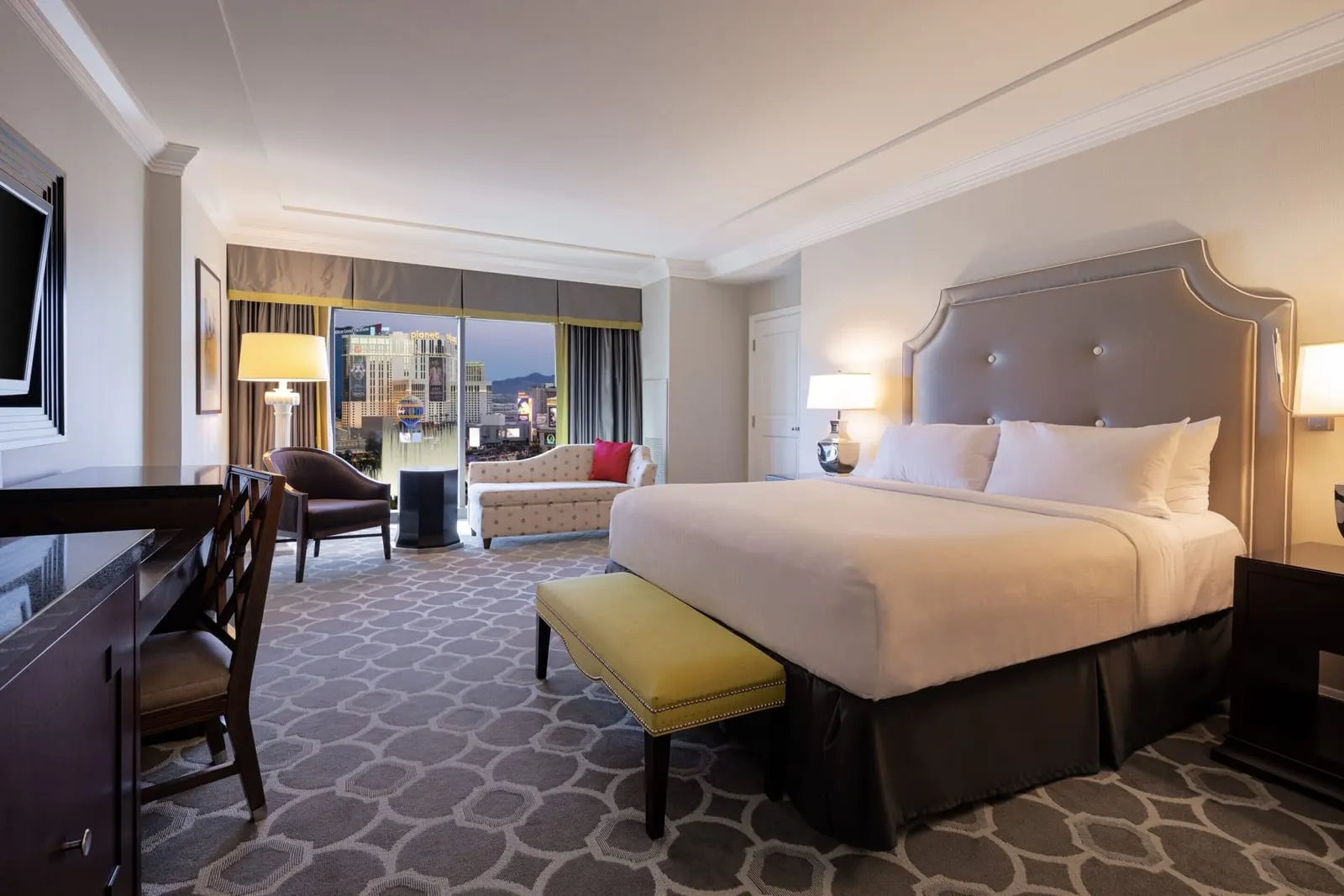 Octavius Executive Suite im Caesars Palace: ein Kingsize-Bett mit einem grauen Kopfteil mit Knopfheftung und einer gelben Bank, ein Schreibtisch sowie eine Chaiselongue und ein Sessel am Fenster