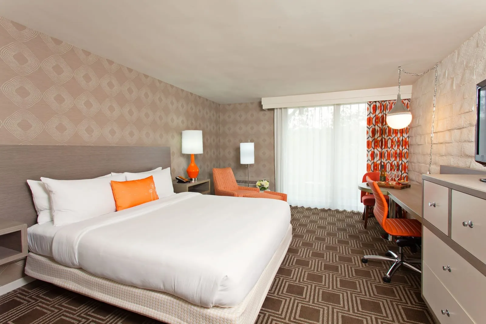 Premium King im The Garland: ein Kingsize-Bett mit einem orangefarbenen Kissen, ein orangefarbener Sessel, ein Schreibtisch und ein Fernseher, neben einem Fenster mit orange gemusterten Vorhängen