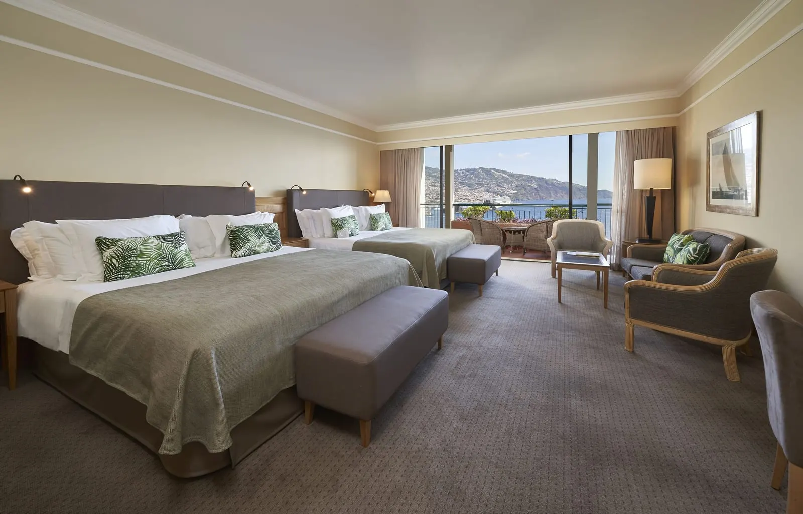Family Room Funchal Bay View at The Cliff Bay, by PortoBay: two large double beds, armchairs and a sofa, and a balcony looking over the harbour to the city on the hills