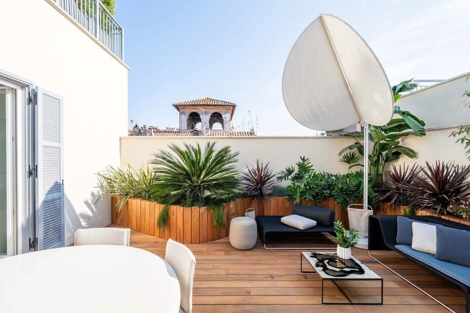 Presidential at ROMEO Roma: a roof terrace with sofas, a dining table and planters, a bell tower beyond