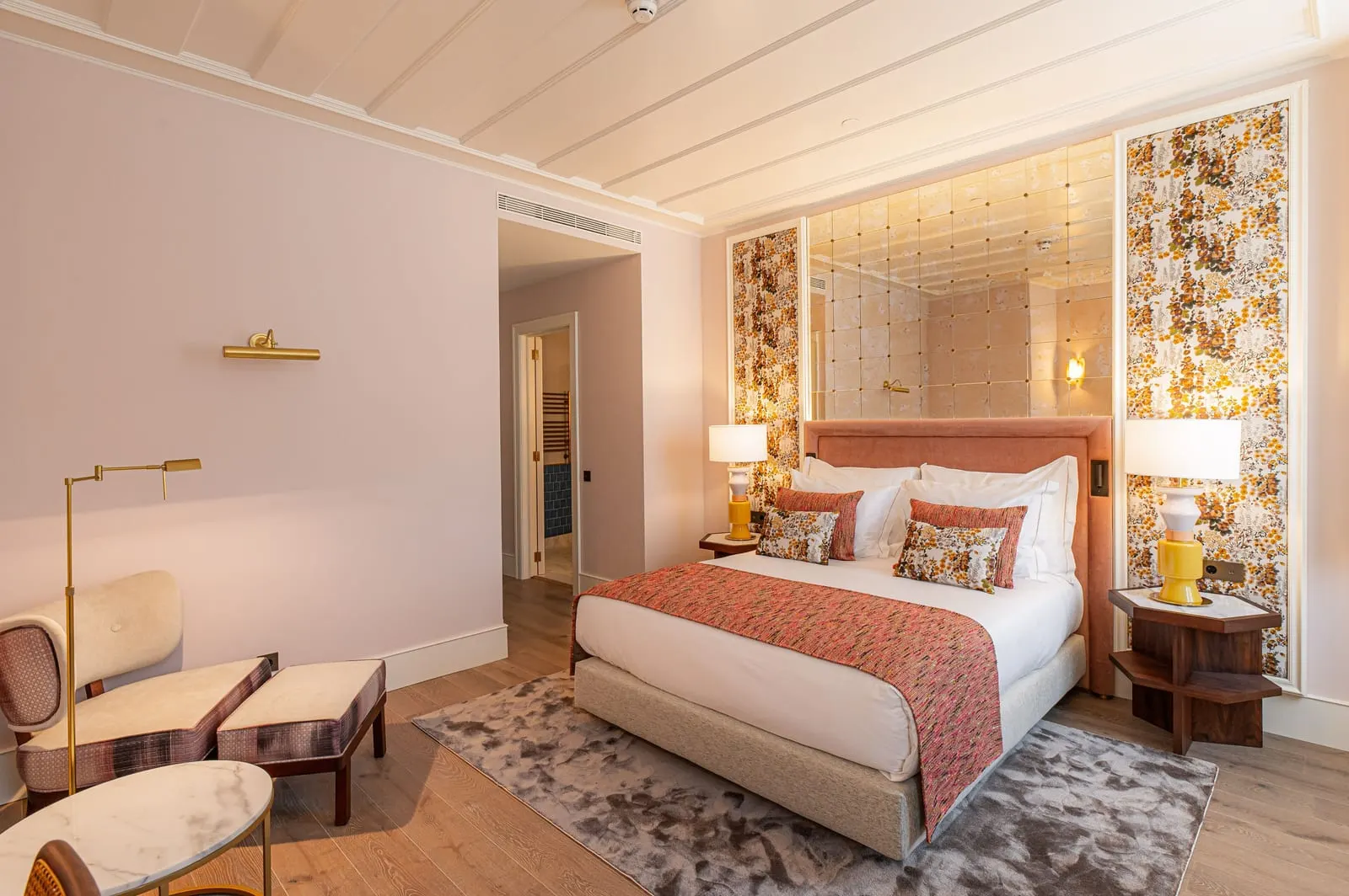 Classic Room at Palácio Ludovice: the bed with a coral throw between floral wall panels, an armchair and a floor lamp