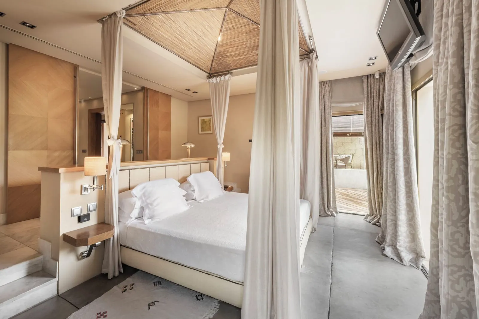 Villa Las Palmeras at Bahía del Duque: the four-poster bed with white curtains under a woven pitched ceiling