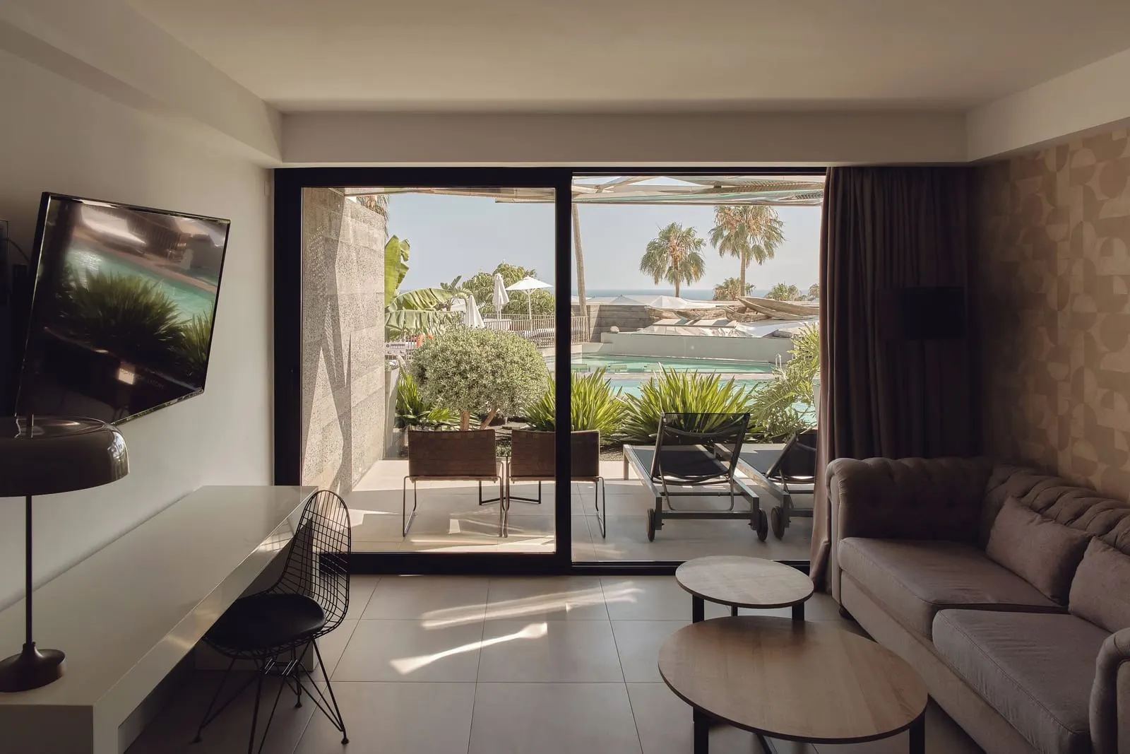 Junior Suite Pool at La Isla y el Mar Hotel Boutique: a sitting area and a television, with glass doors onto a terrace above the pool area