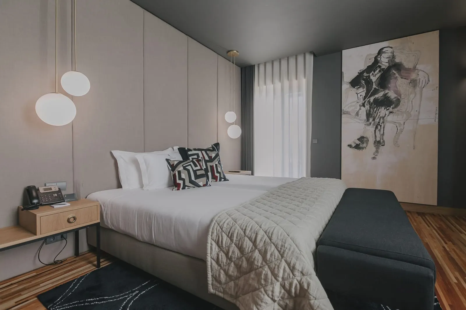 Deluxe Junior Suite at Torel Avantgarde: the bed with globe pendant lights, a bench and a large sketch on the wall