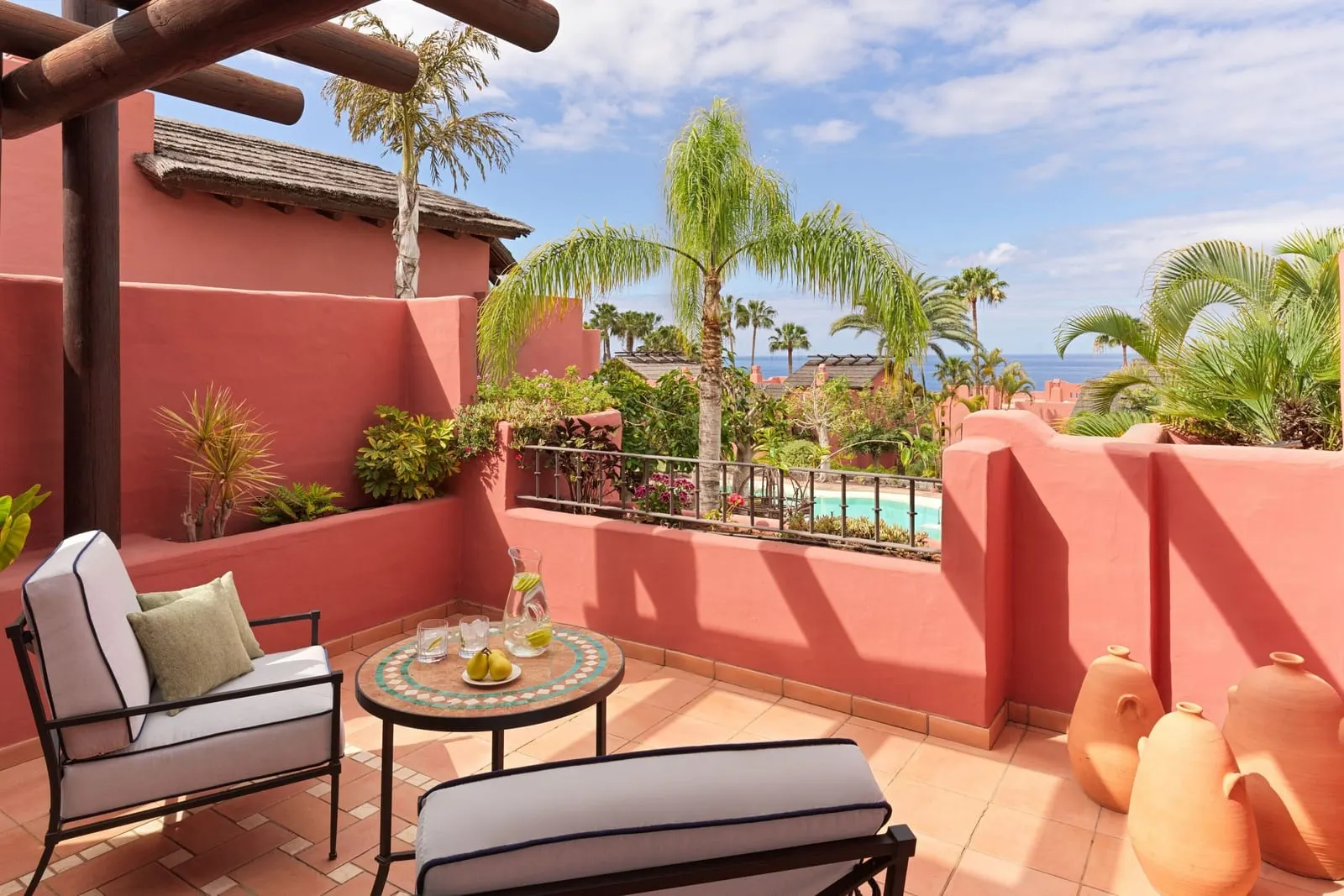 Retreat Deluxe Room, Adults Only, Ocean View at the Ritz-Carlton Abama: a terrace with a lounger and a chair above palms