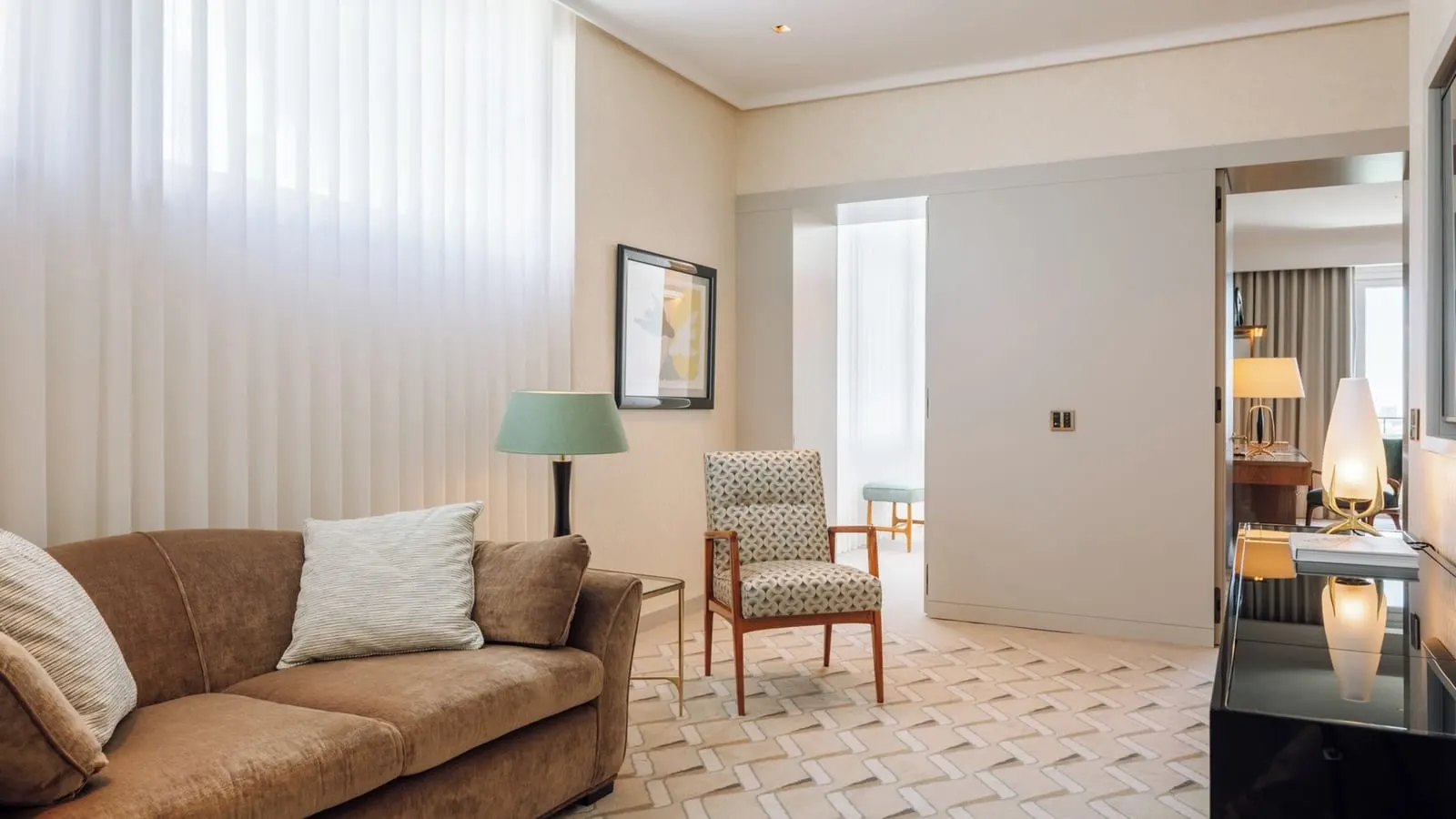 One-Bedroom Suite at Four Seasons Ritz Lisbon: the living room, with a brown sofa, an armchair and a doorway through