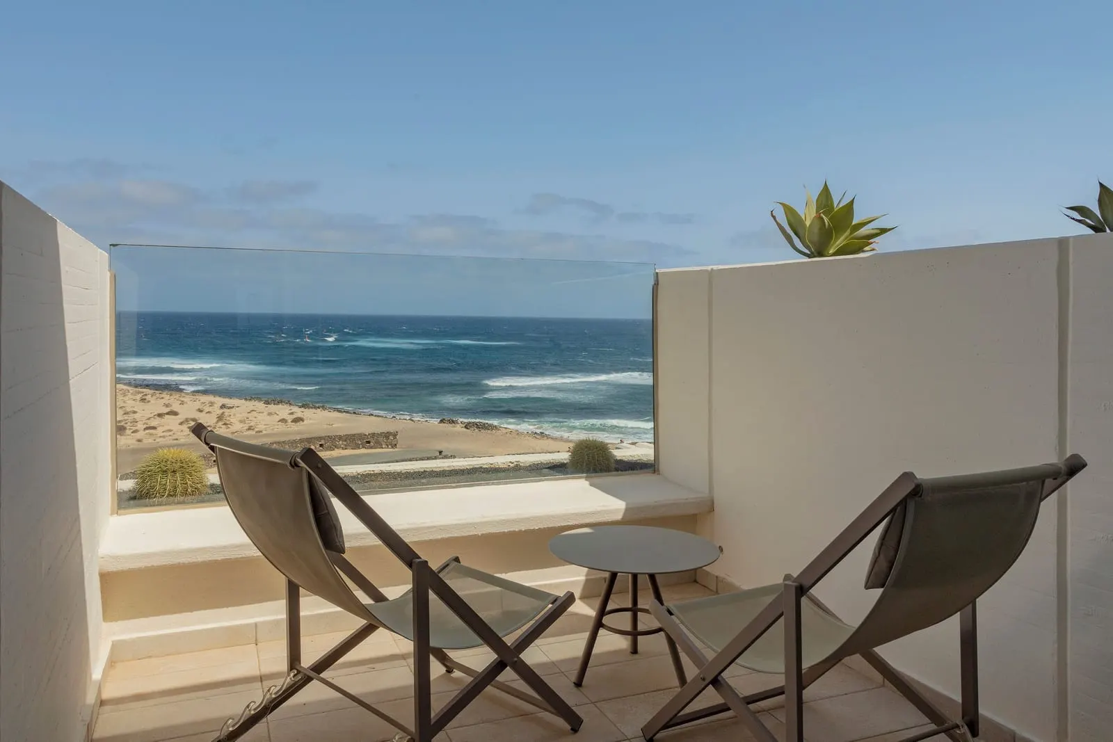Premium Ocean Front at Paradisus Salinas Lanzarote: a terrace with two chairs and a table facing the sea and a sandy beach