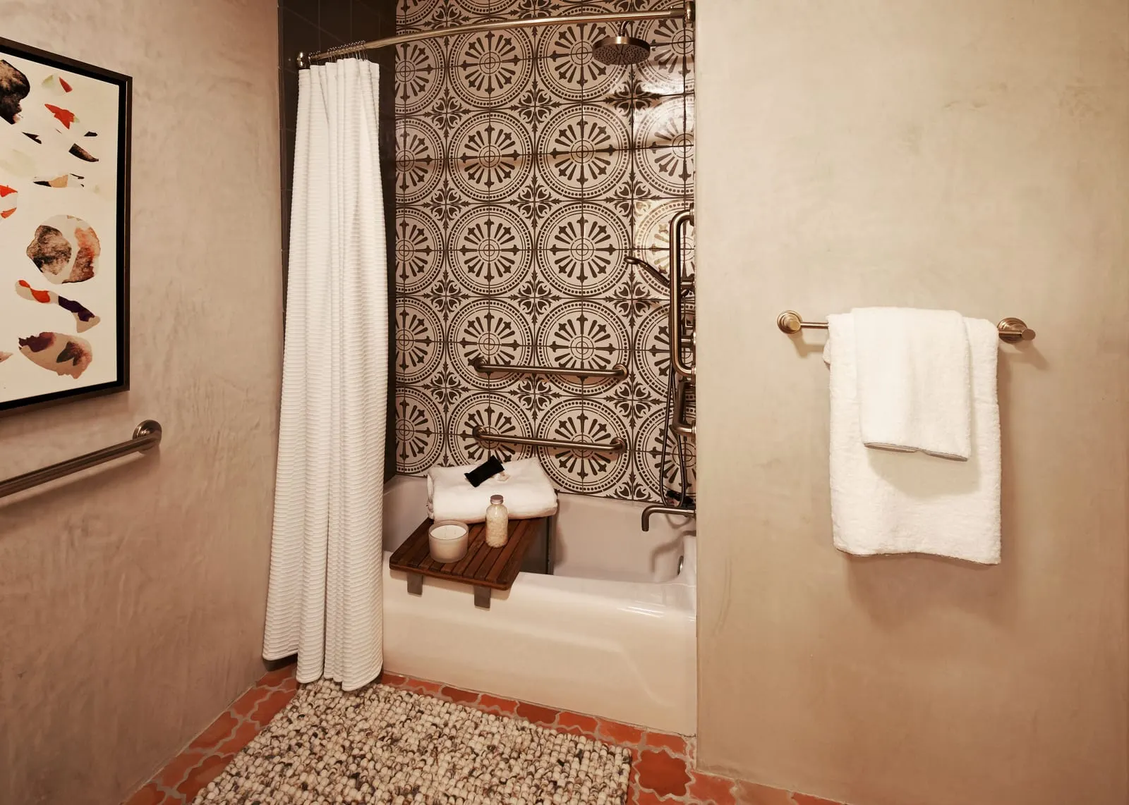 1 Queen Bed ADA with Tub im Hotel Figueroa: eine Badewanne mit einem Sitz aus Holzlatten, Haltegriffe an der Wand mit gemusterten Fliesen und eine Handbrause, mit einem zur Seite gezogenen weißen Vorhang