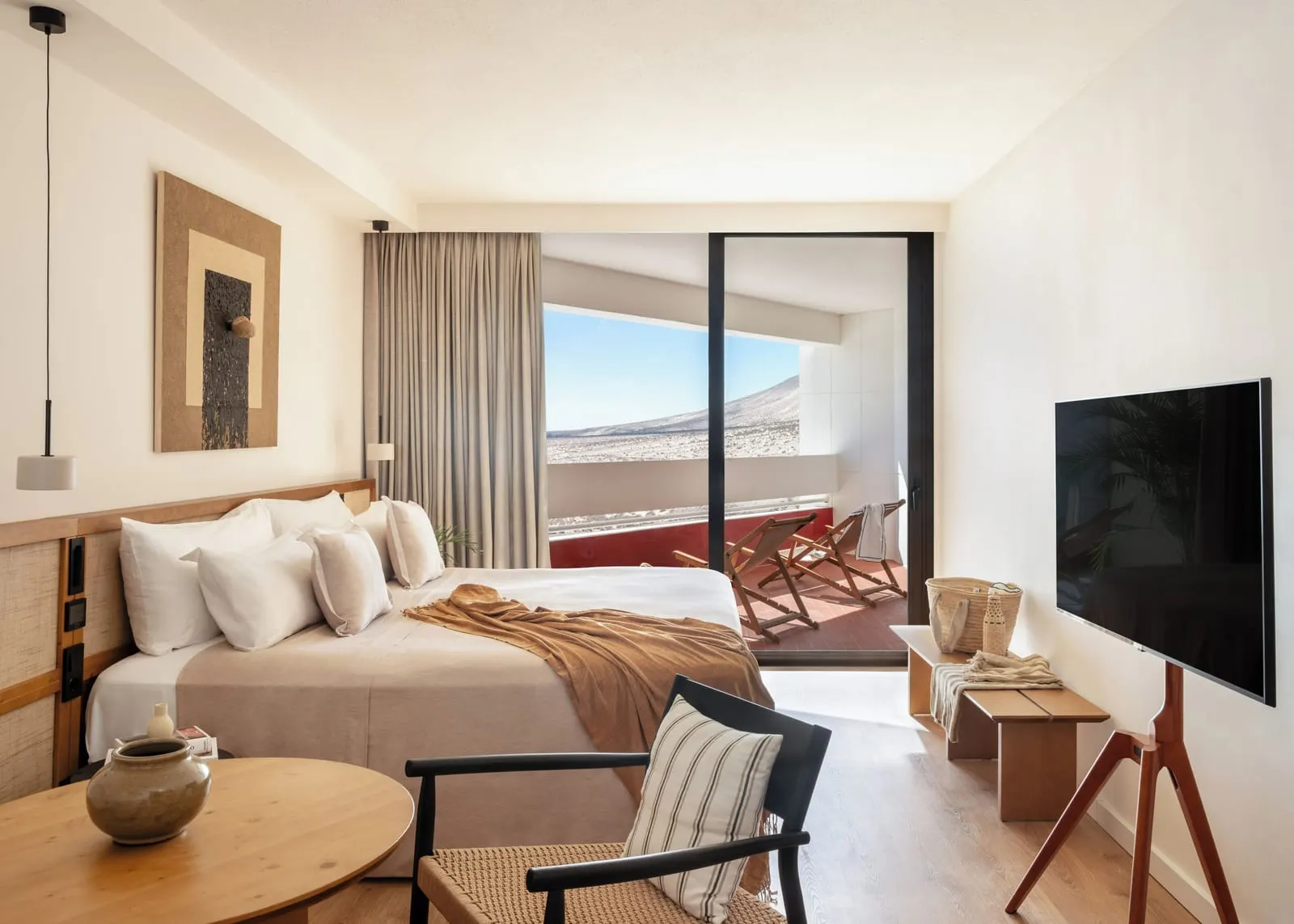 Premium Room at Paradisus by Meliá Fuerteventura: a king-size bed, a round table and a television on a stand, with a glass door open to a terrace with two folding chairs