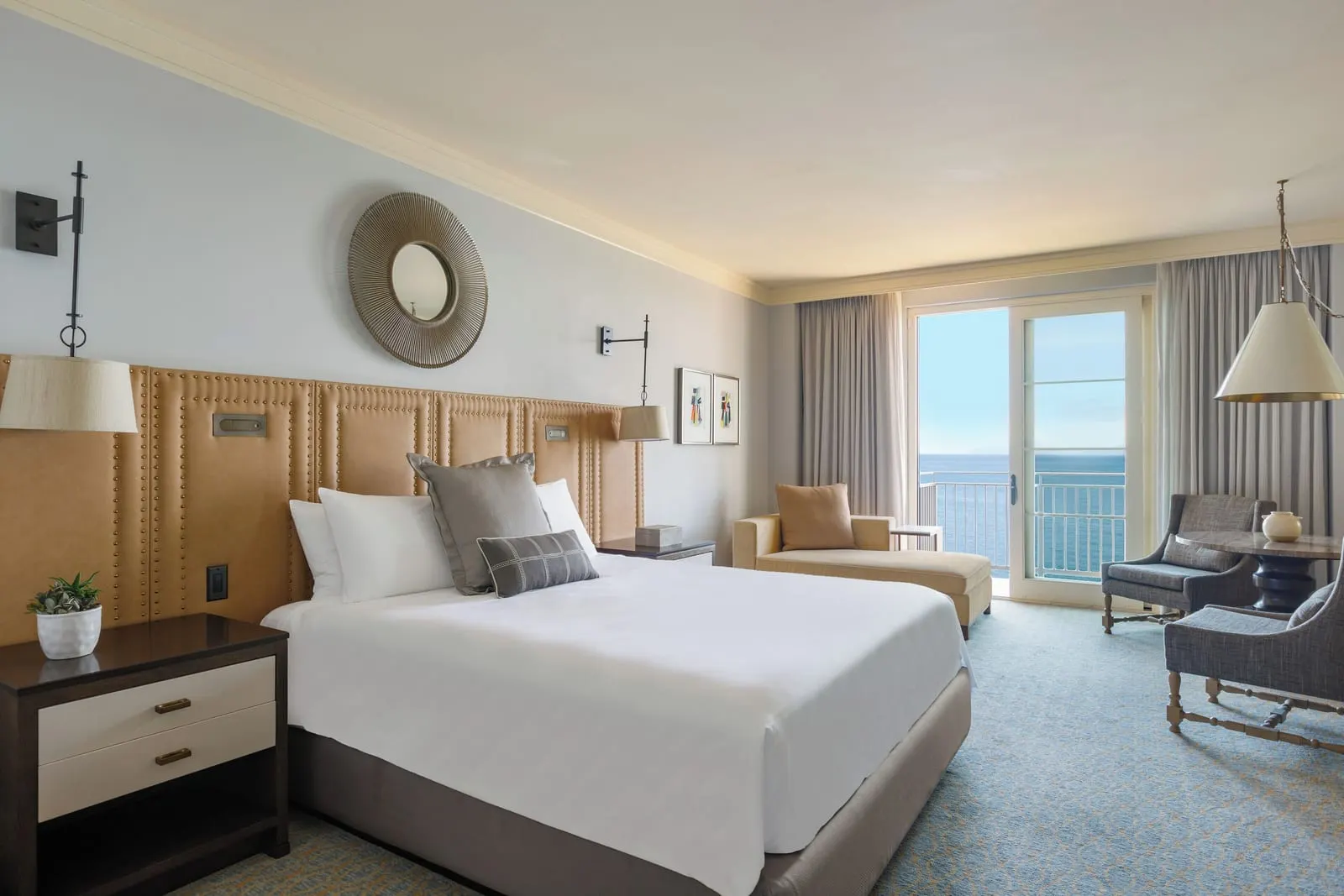 Hotel King Guestroom, Ocean Front at Terranea Resort: a king bed with a tan quilted headboard and a seating area by glass doors onto a balcony with the sea beyond