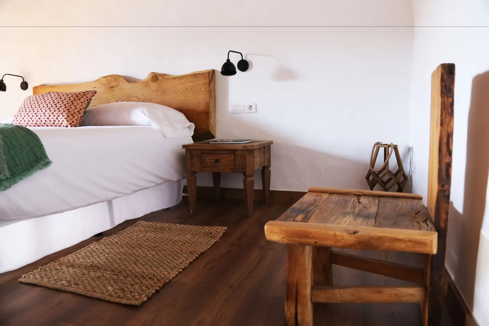 Suite 06 at Hotel Boutique Palacio Ico: a bed with a rough-hewn wooden headboard, a side table and dark wooden floors