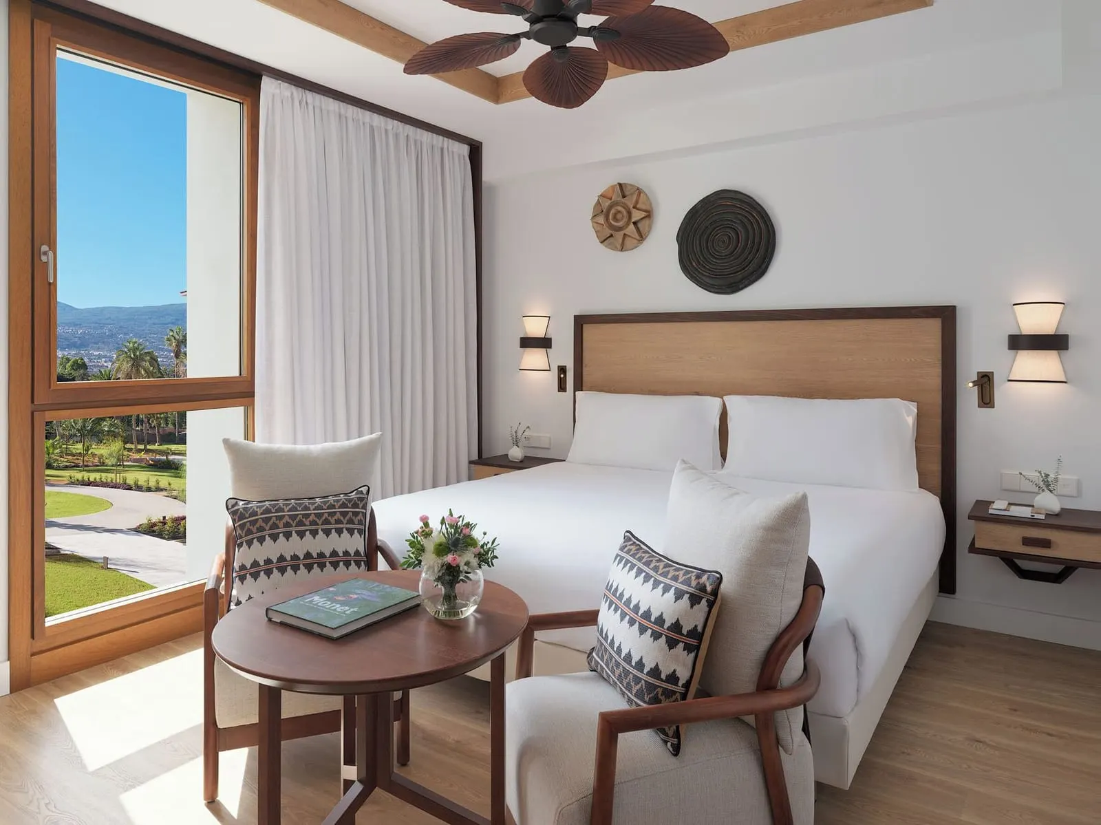 Double Deluxe Room Mountain View at Gran Hotel Taoro: the bed, two armchairs and a window onto palms and hills
