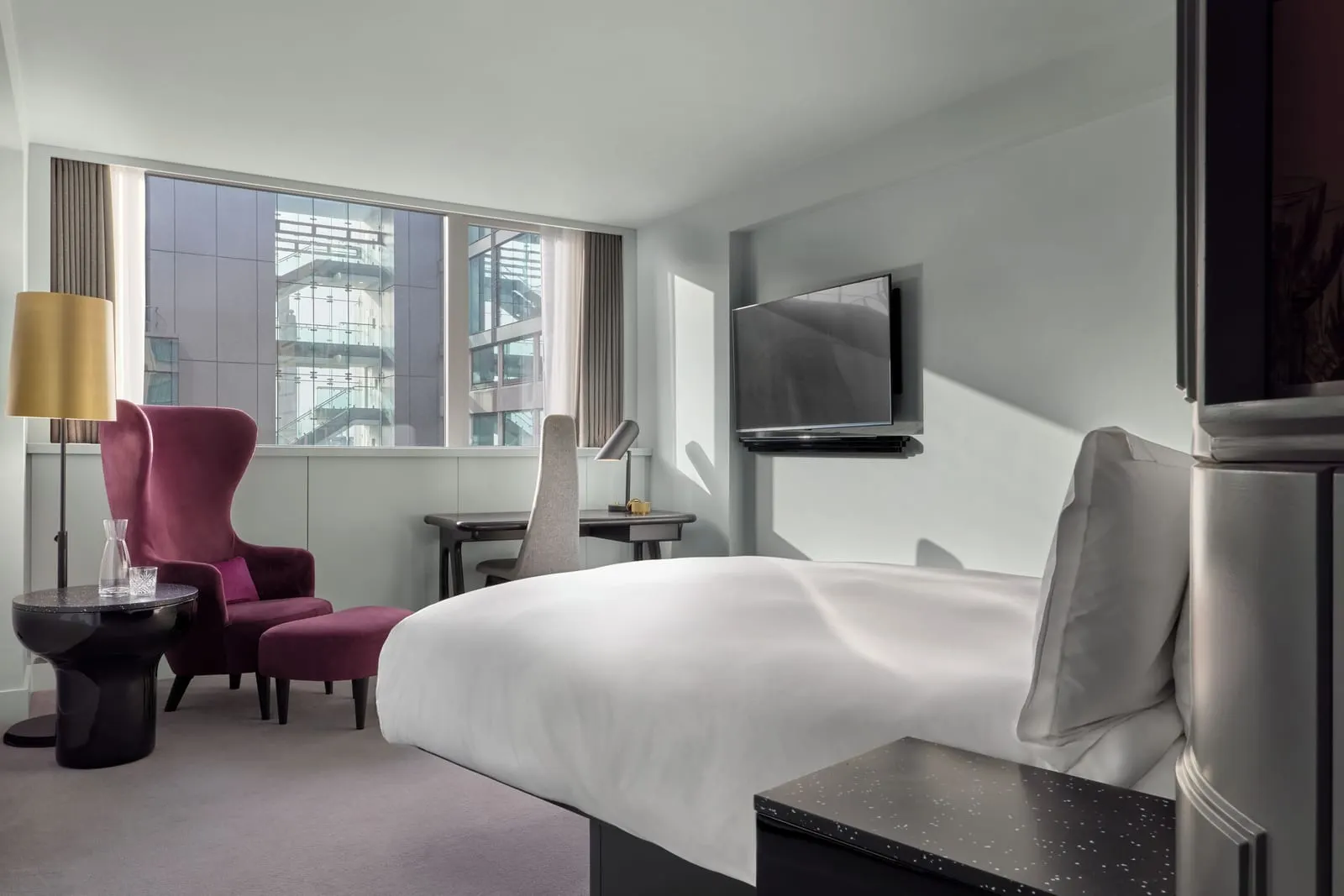 Standard Room at Sea Containers London: the bed, a purple wing chair, a desk and a window onto nearby buildings