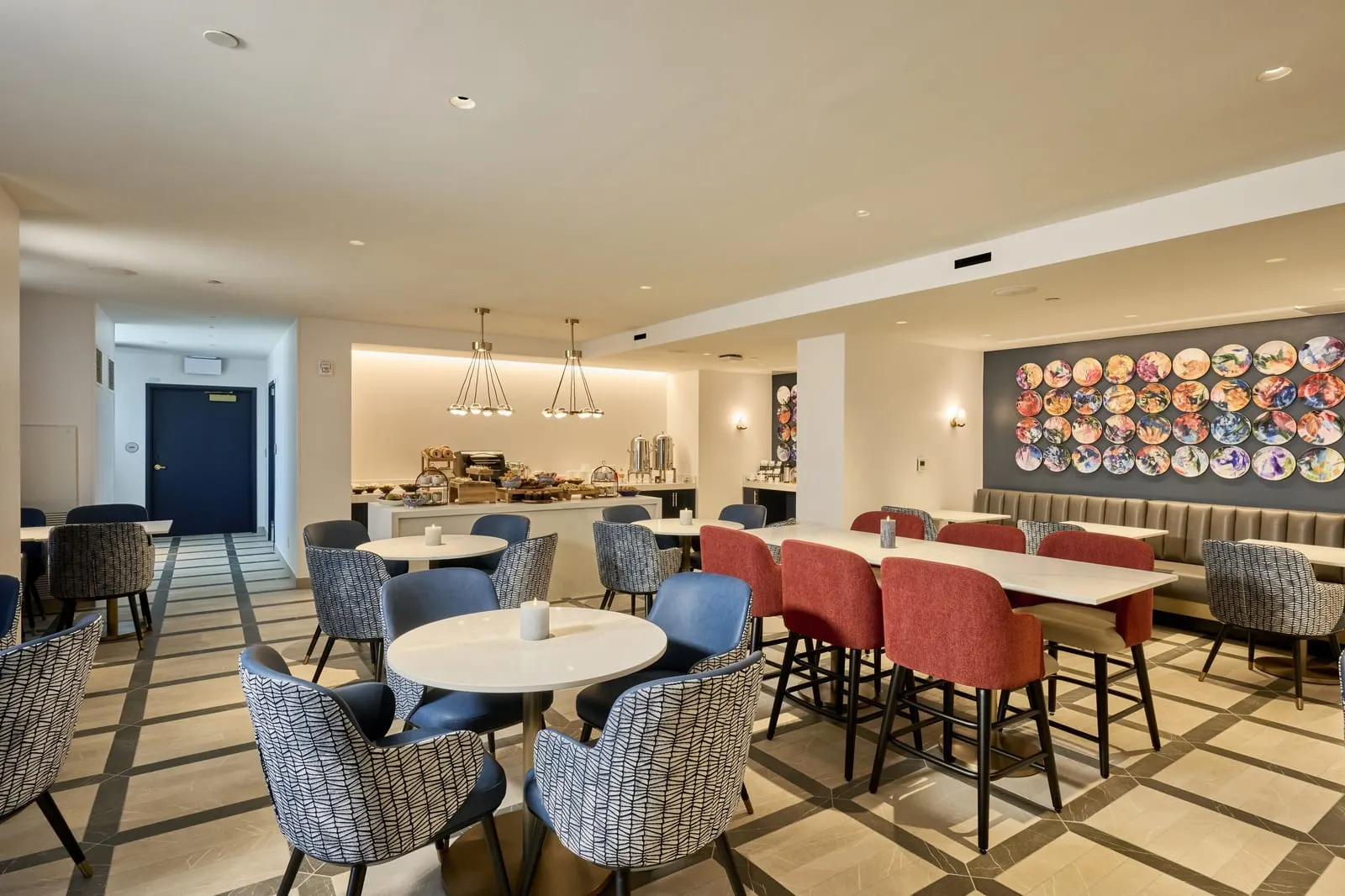 Skyline View Club Level 2 Queen Beds at Universal Helios Grand Hotel: the Club Lounge that comes with the room, with a counter of pastries and coffee, round tables and a wall of painted plates