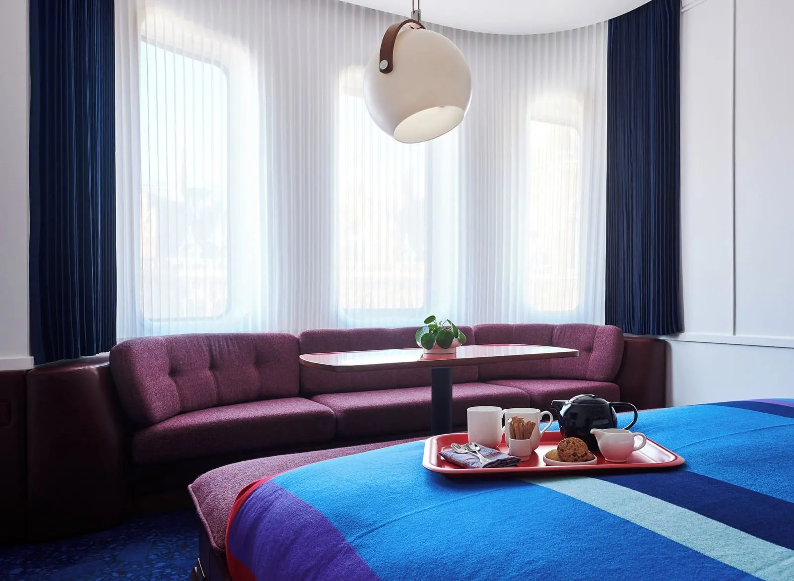 Premium King View at The Standard, London: the bed with a breakfast tray and a curved sofa in the bay, with sheer blinds drawn